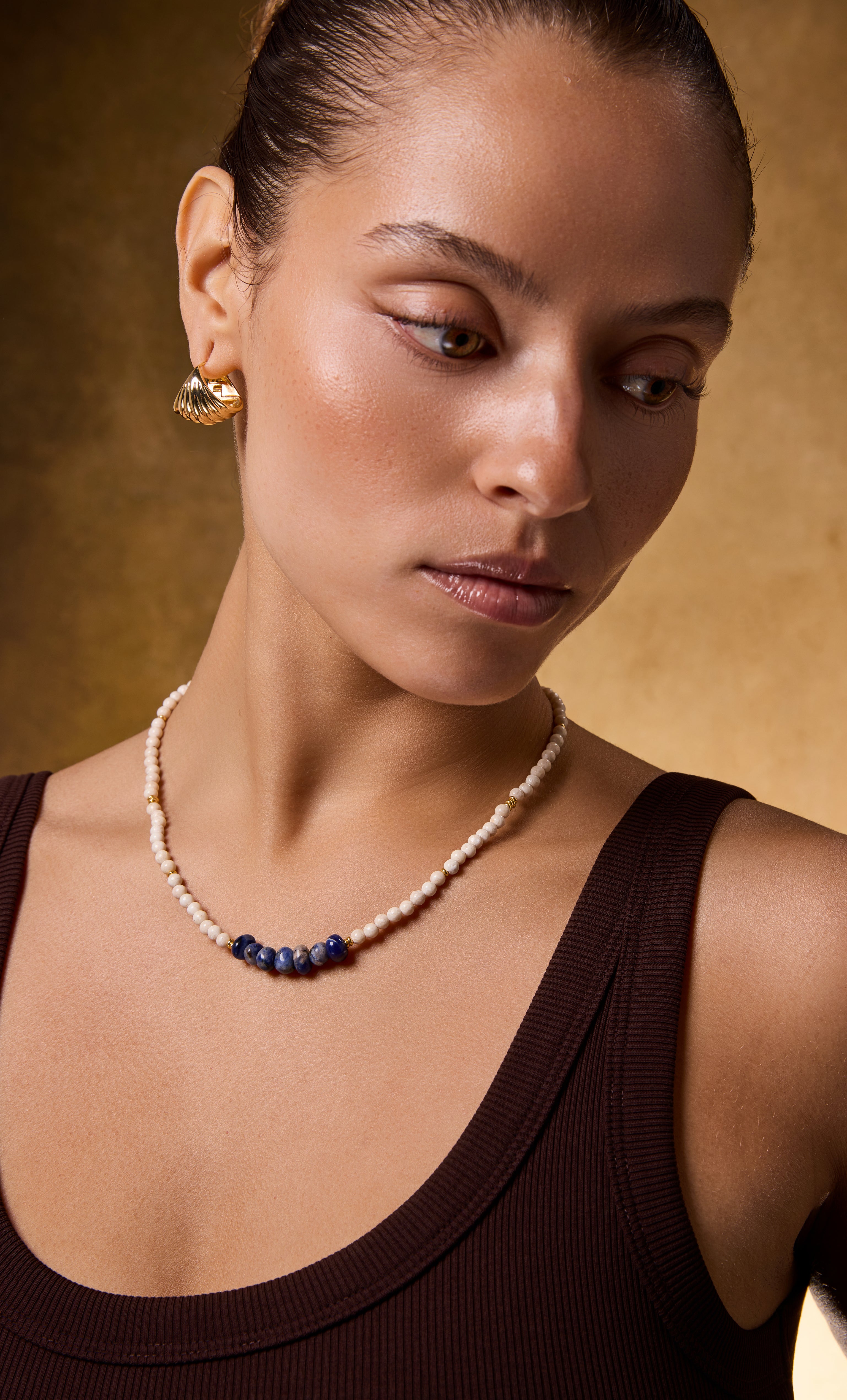 Sculpt 18K gold fill shell huggie earrings by Tunik paired with gold fill necklace featuring white and navy beads, elegant.