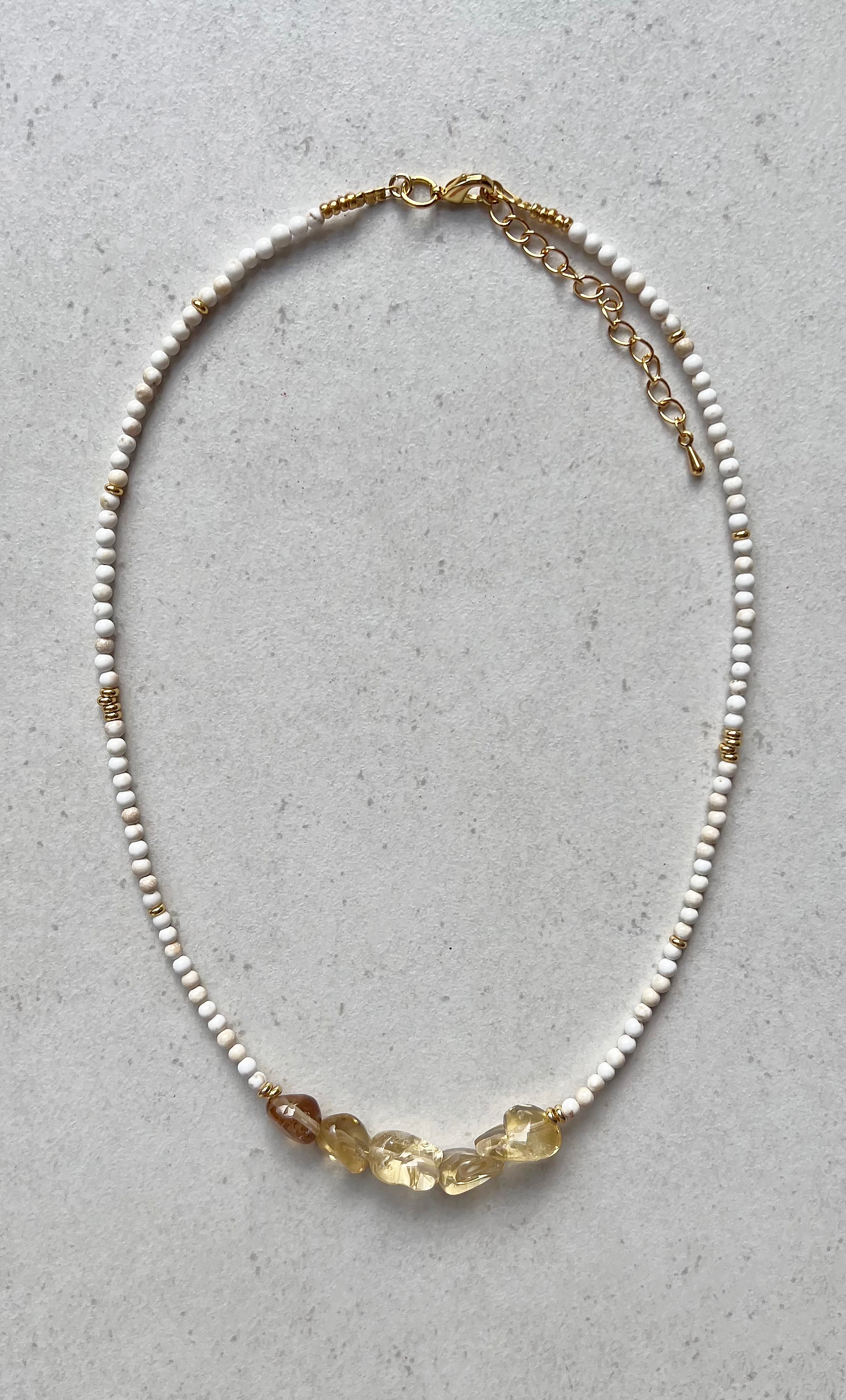 A necklace with white beads and gold-colored beads, featuring multiple citrine stones, with gold fill and a parrot clasp.