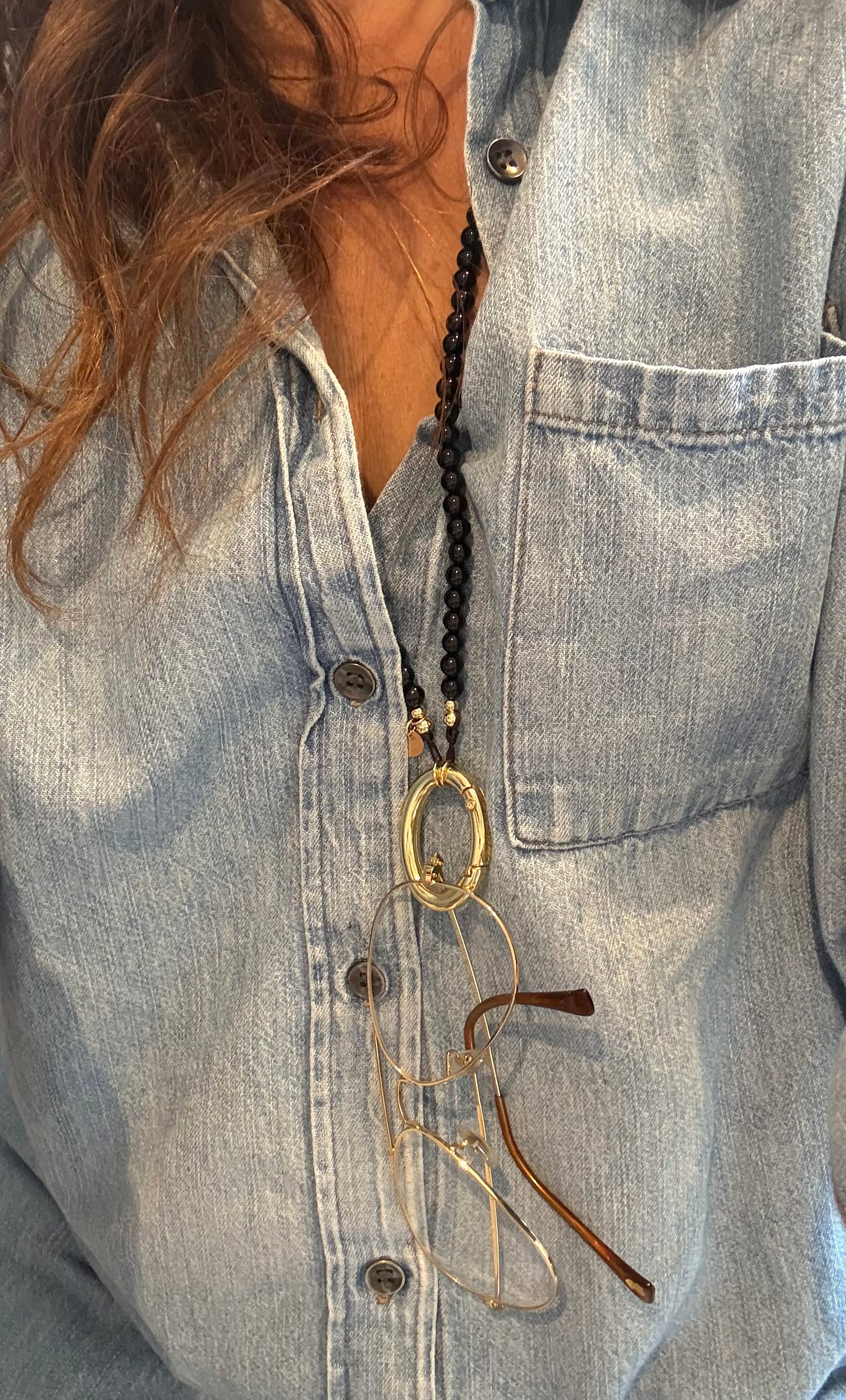 Tunik gold fill necklace with agate stone beads holding eyeglasses and keys, layered over denim shirt.