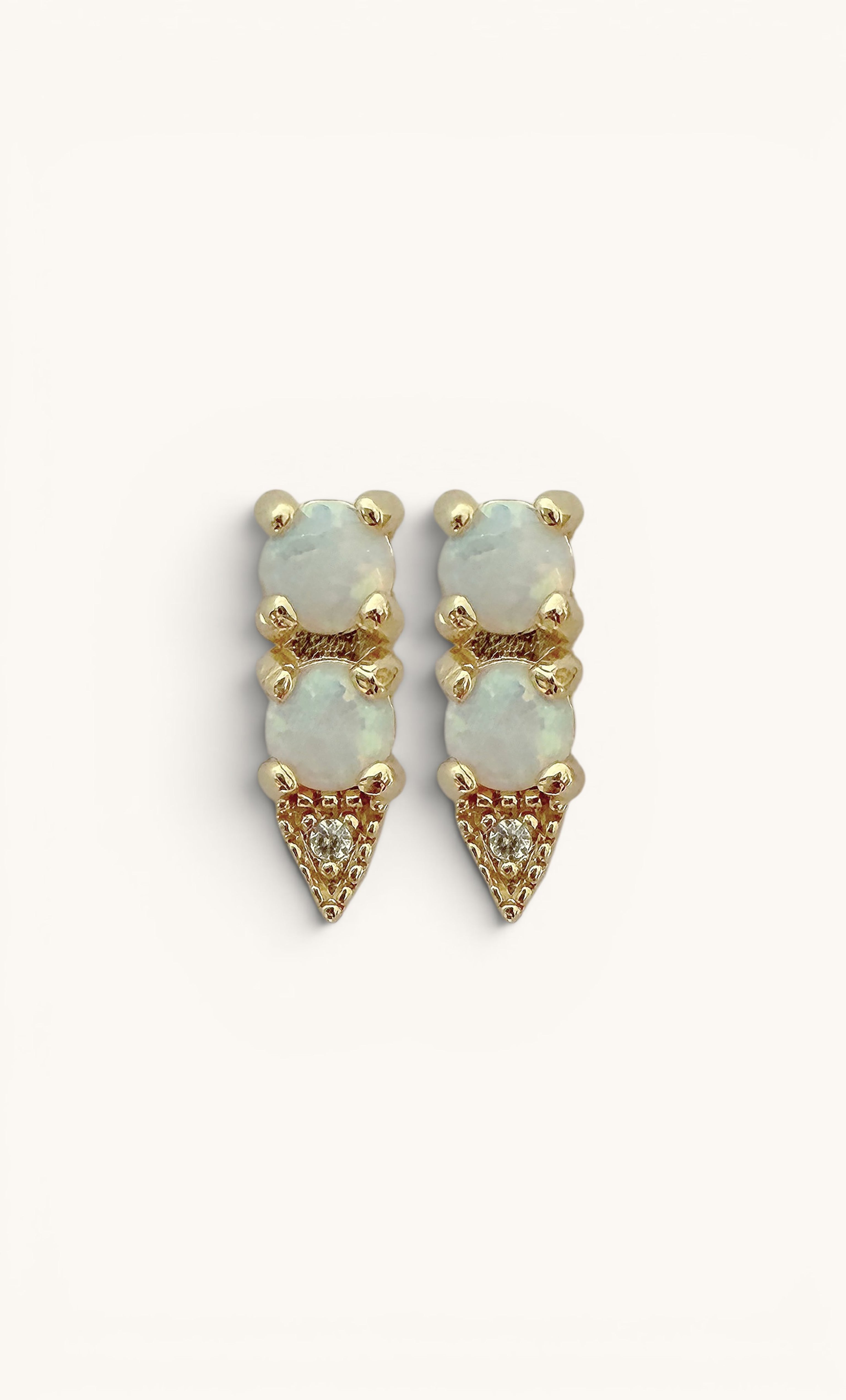 Gold fill arrow-shaped studs featuring white opal stones in a vertical triple setting.