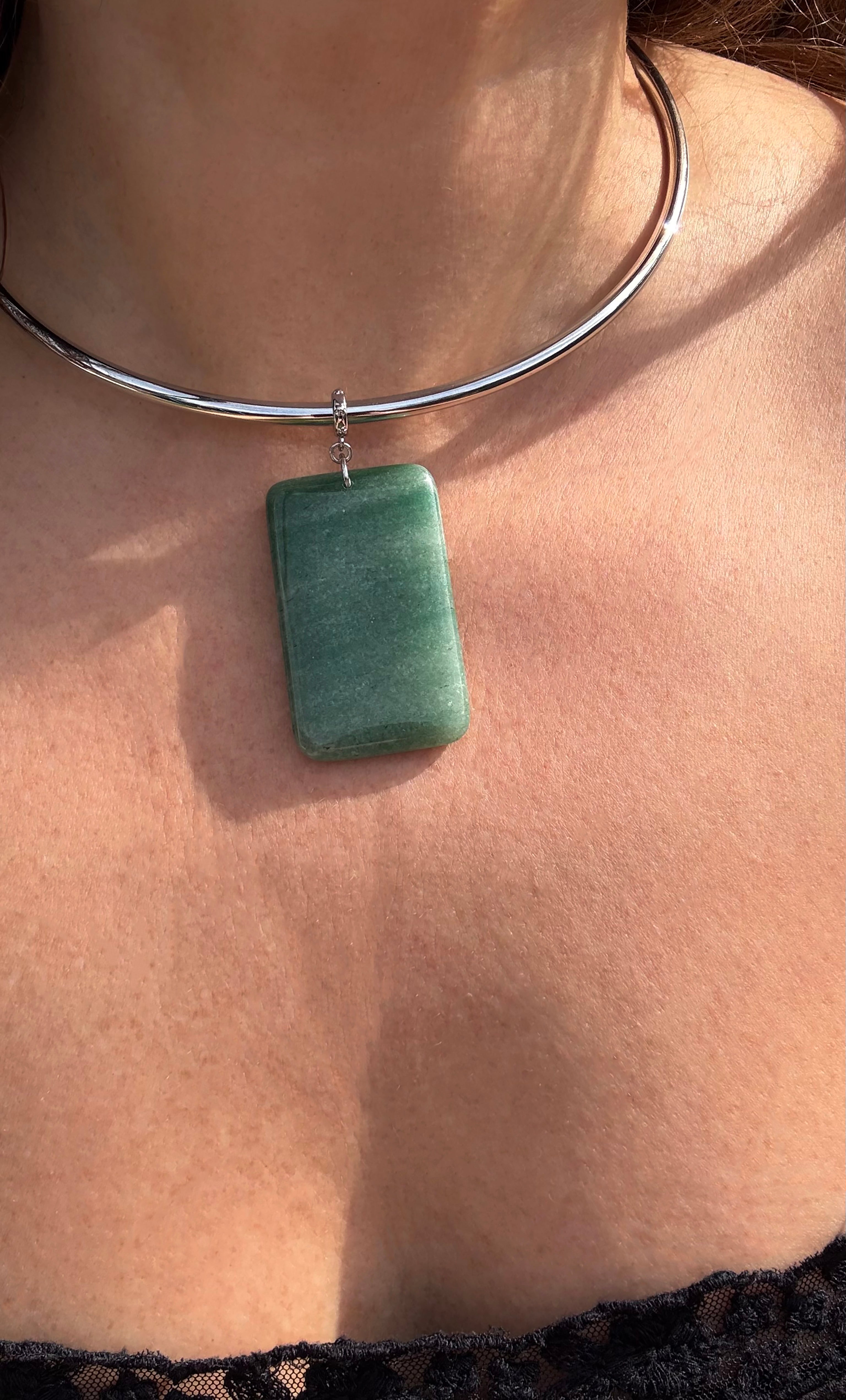 Silver collar necklace with a rectangular green aventurine stone pendant on bare skin.