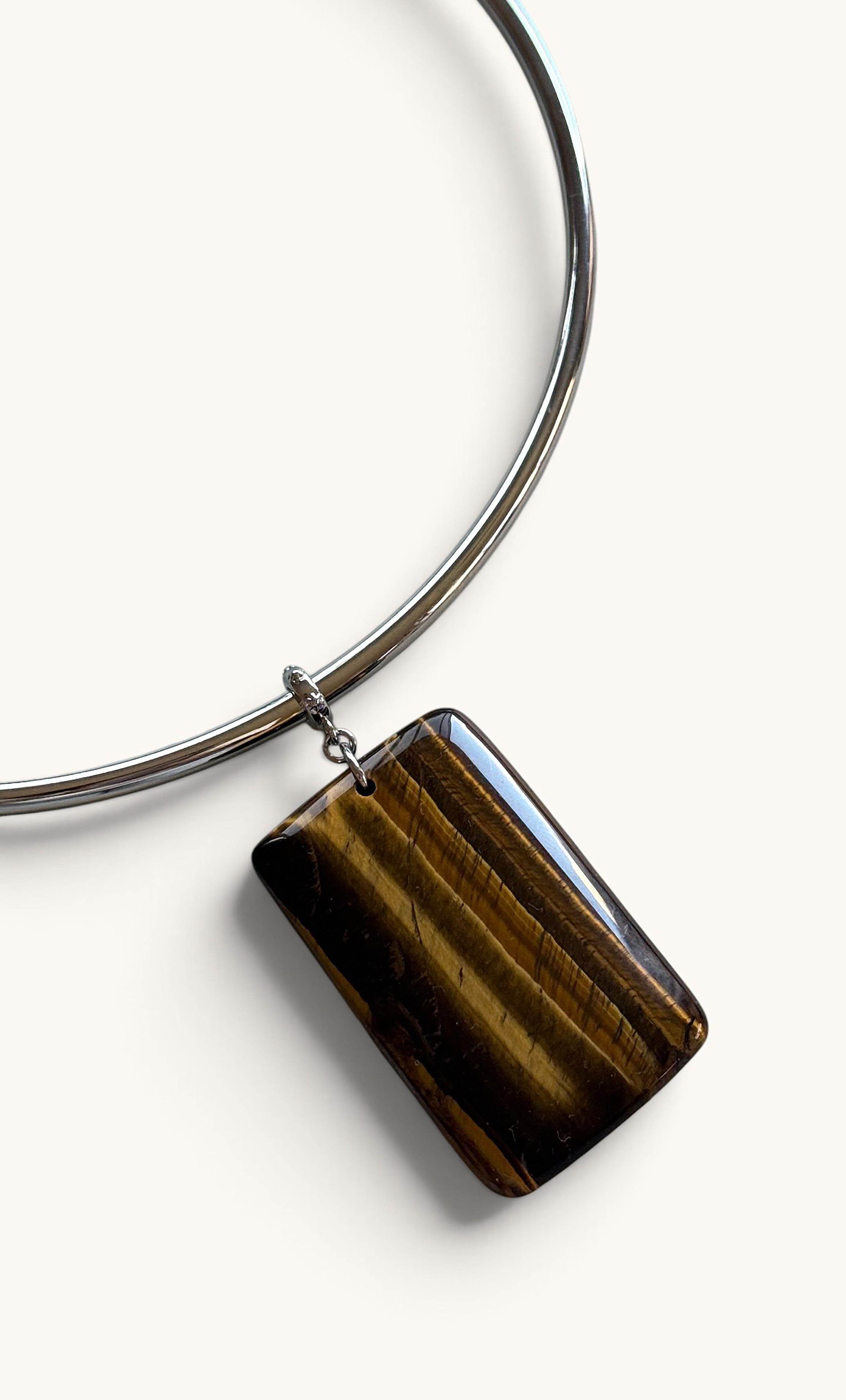 Silver collar necklace with rectangular polished tiger's eye stone pendant.
