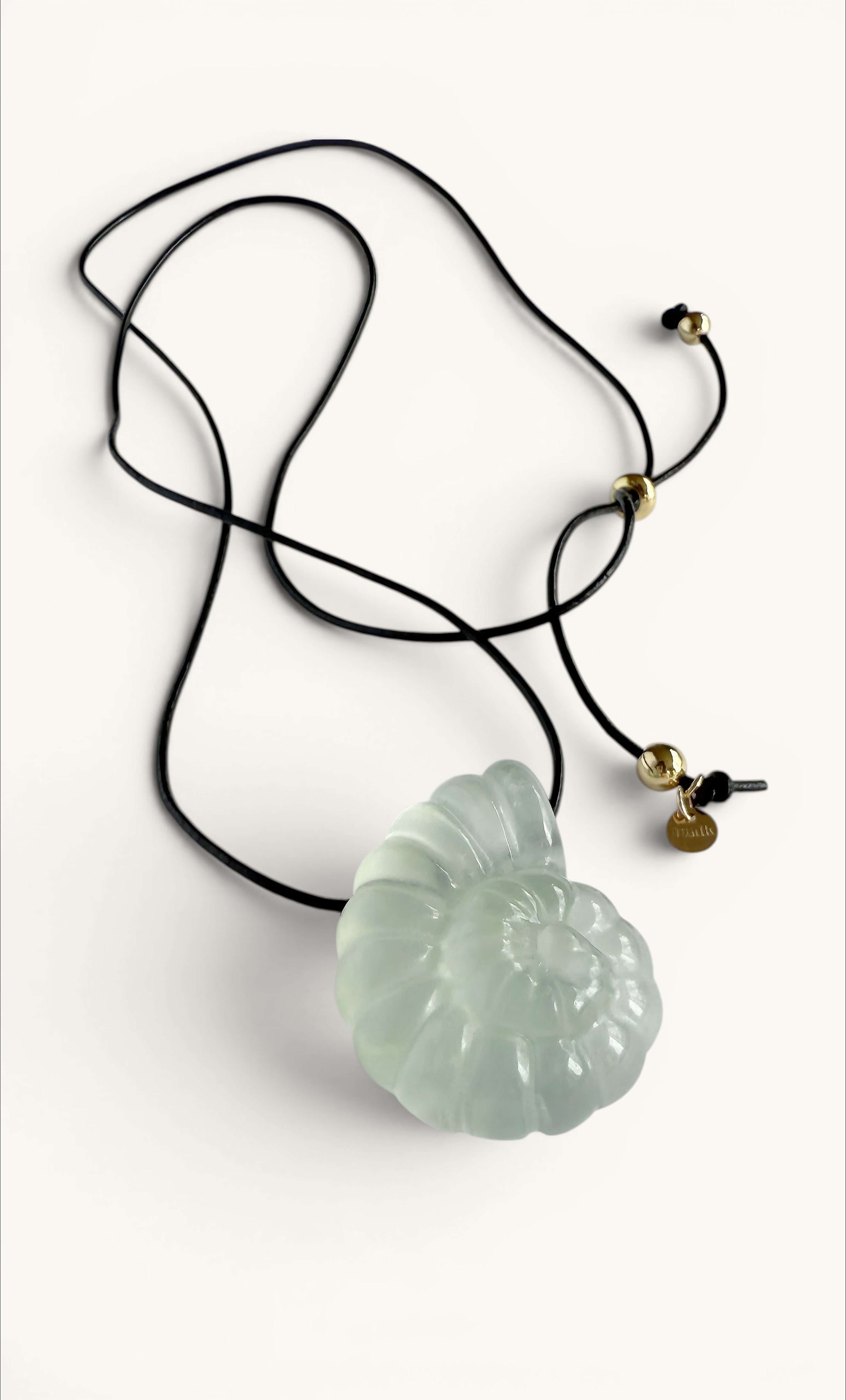 Light green carved fluorite nautilus shell pendant on black adjustable cord necklace with gold fill accents.