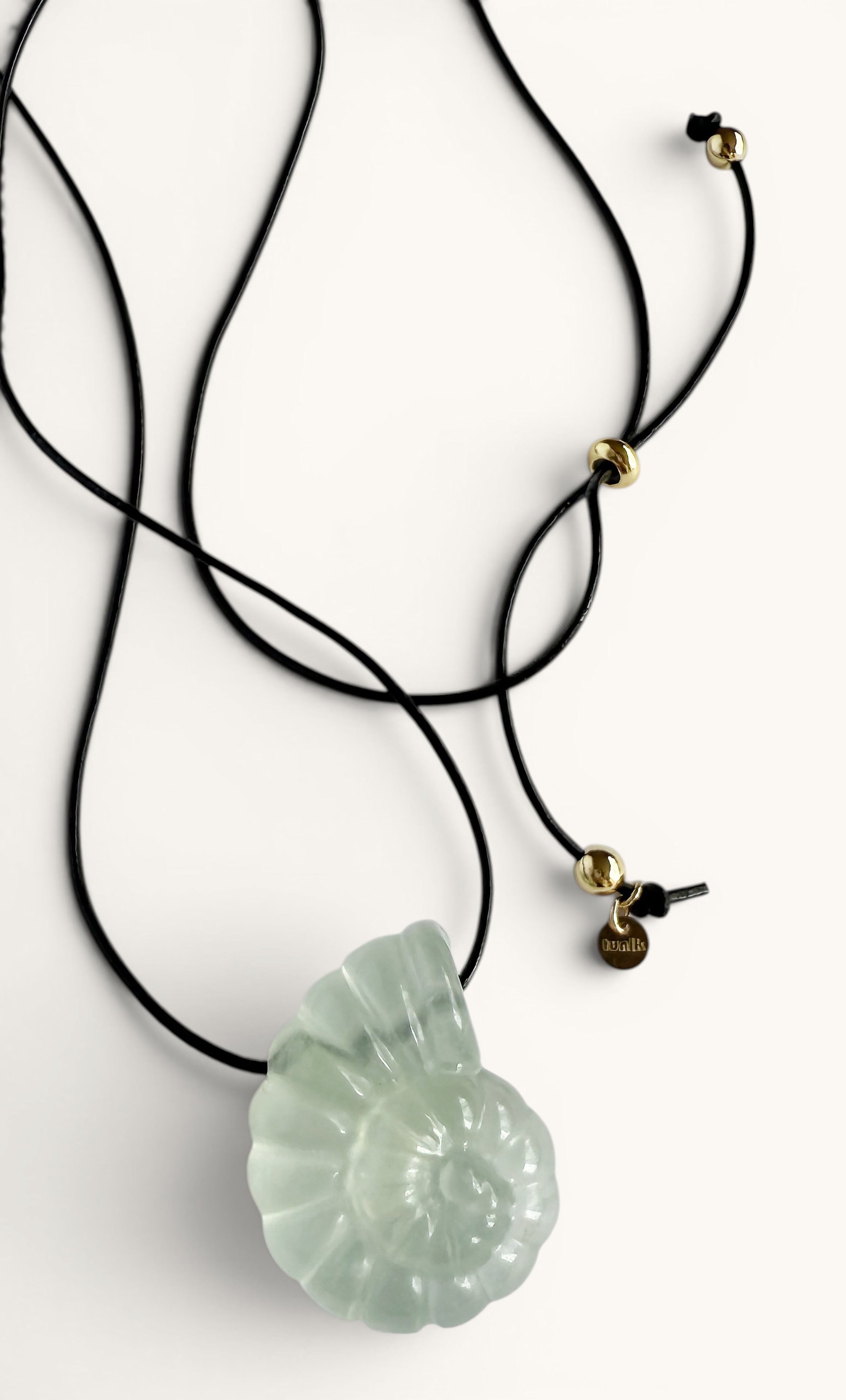 Light green carved nautilus fluorite stone pendant on black cord with gold fill accents.
