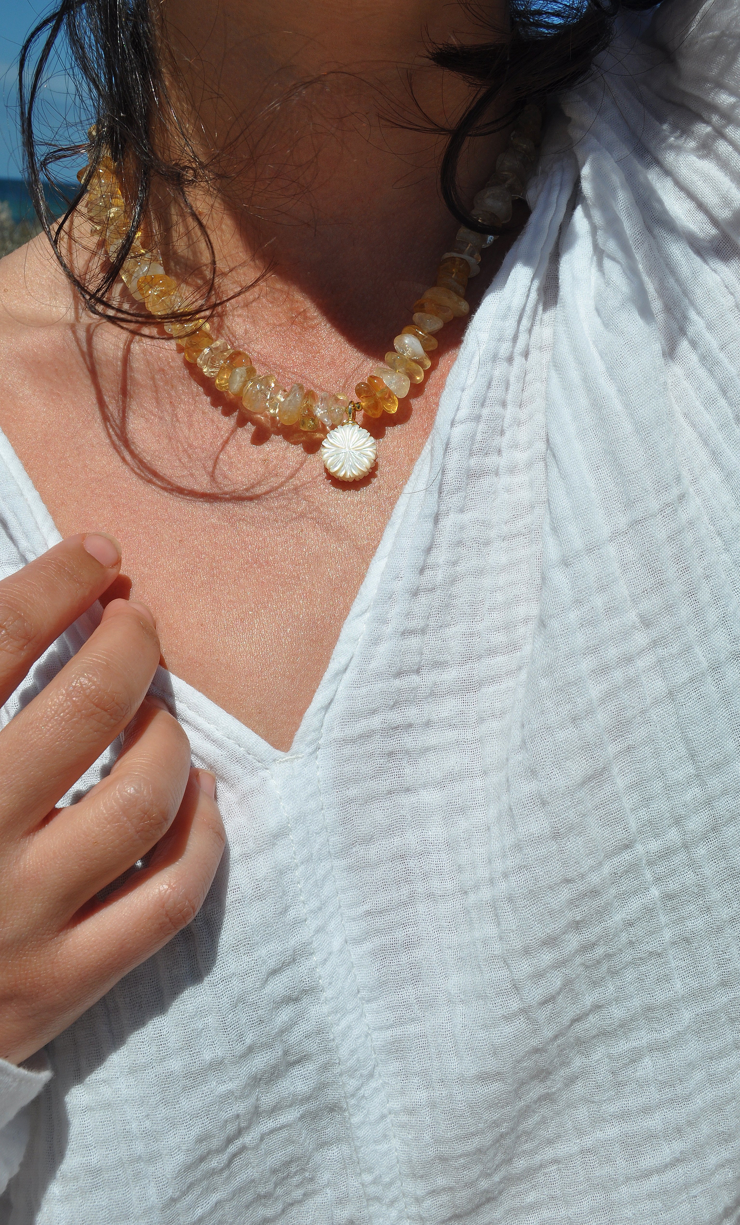 Tunik gold fill necklace with yellow citrine stones and flower carved pendant, styled with white top.