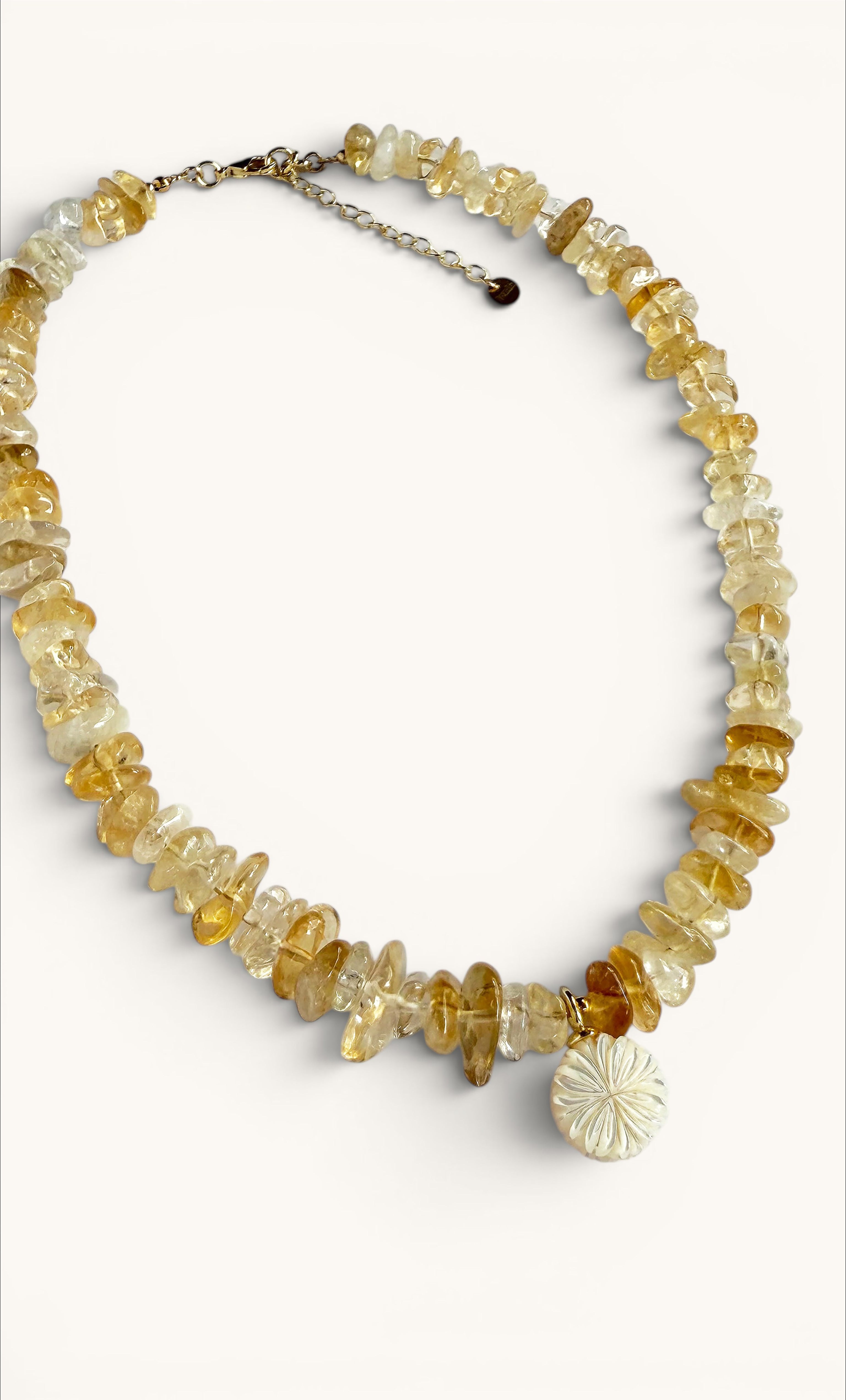 Gold-filled necklace with irregular yellow citrine stones and a carved flower pendant.
