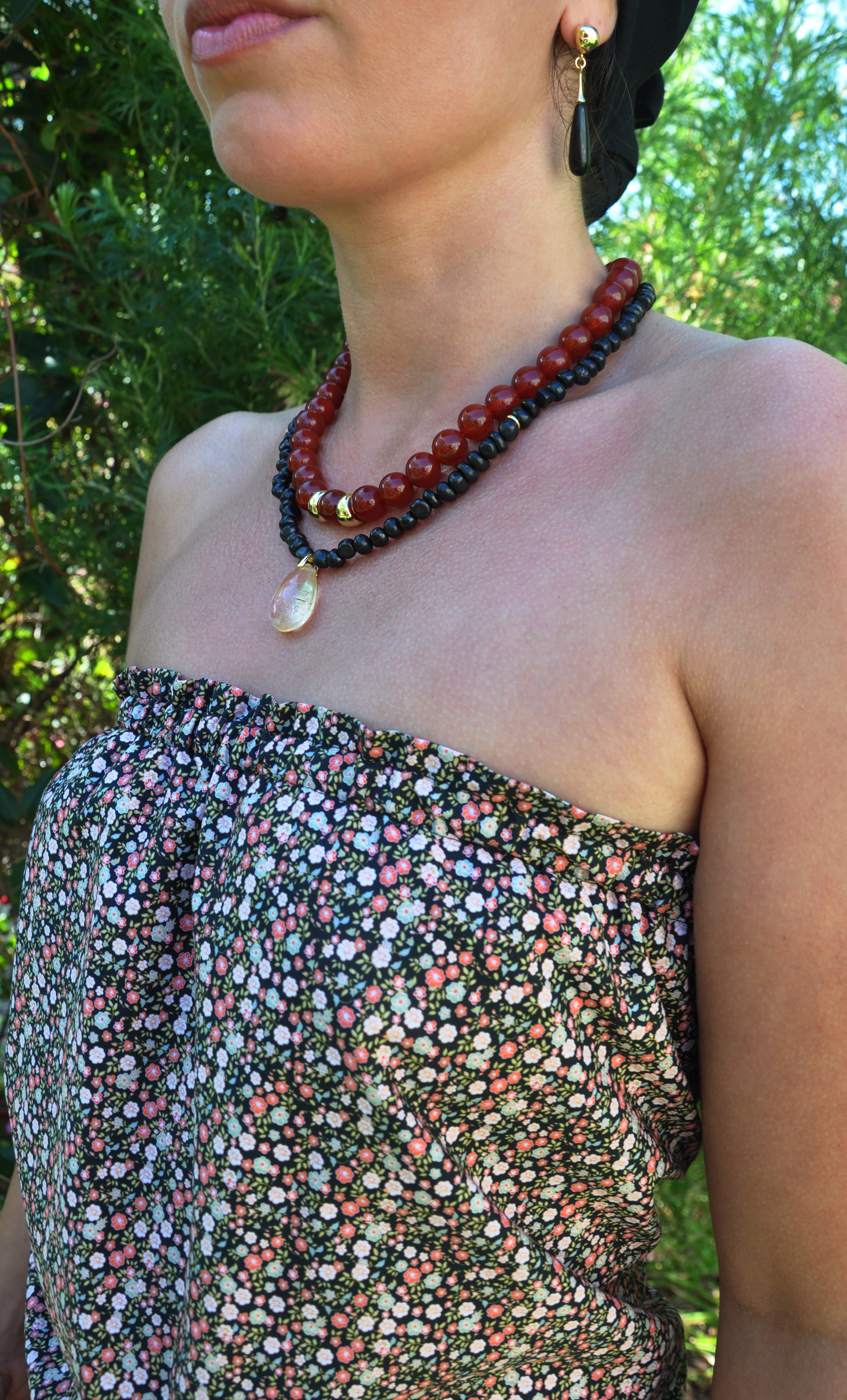 Tunik gold fill necklace with natural shungite pebble beads and citrine pendant against floral top, jewellery gifts.