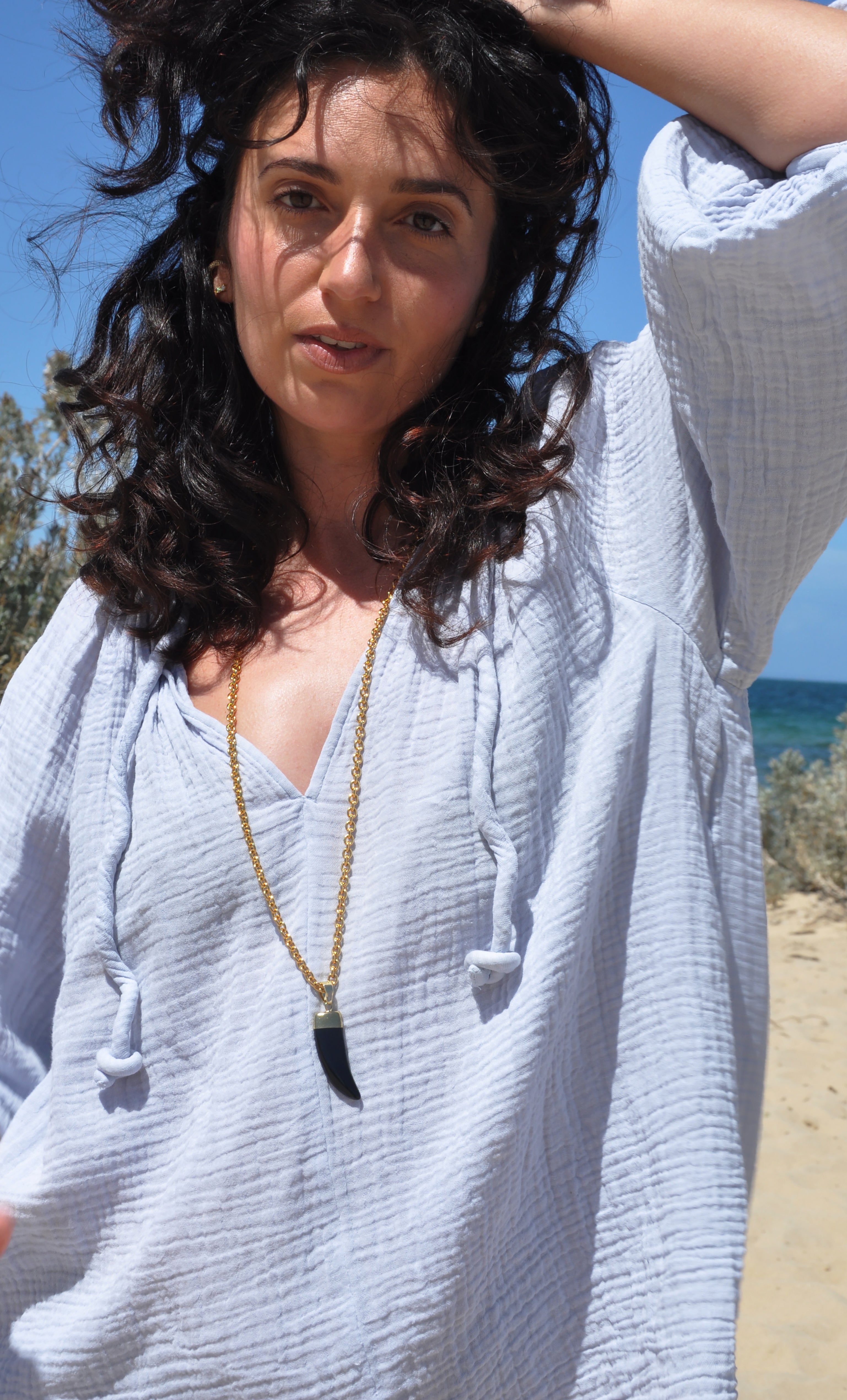 Long gold fill necklace by Tunik the Label with carved agate horn pendant, styled with light blue top, jewellery gift idea.