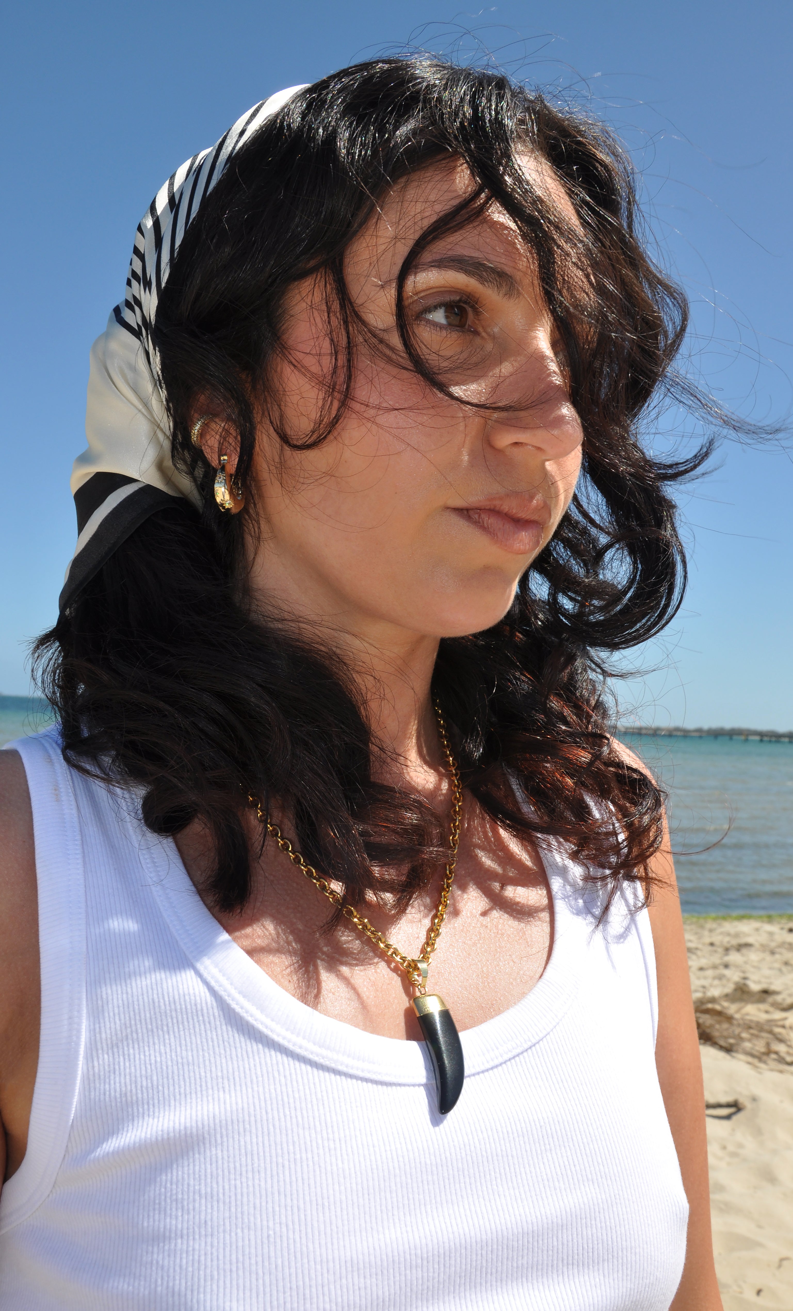 Tunik gold fill necklace with carved agate horn pendant worn with white tank top by the sea.