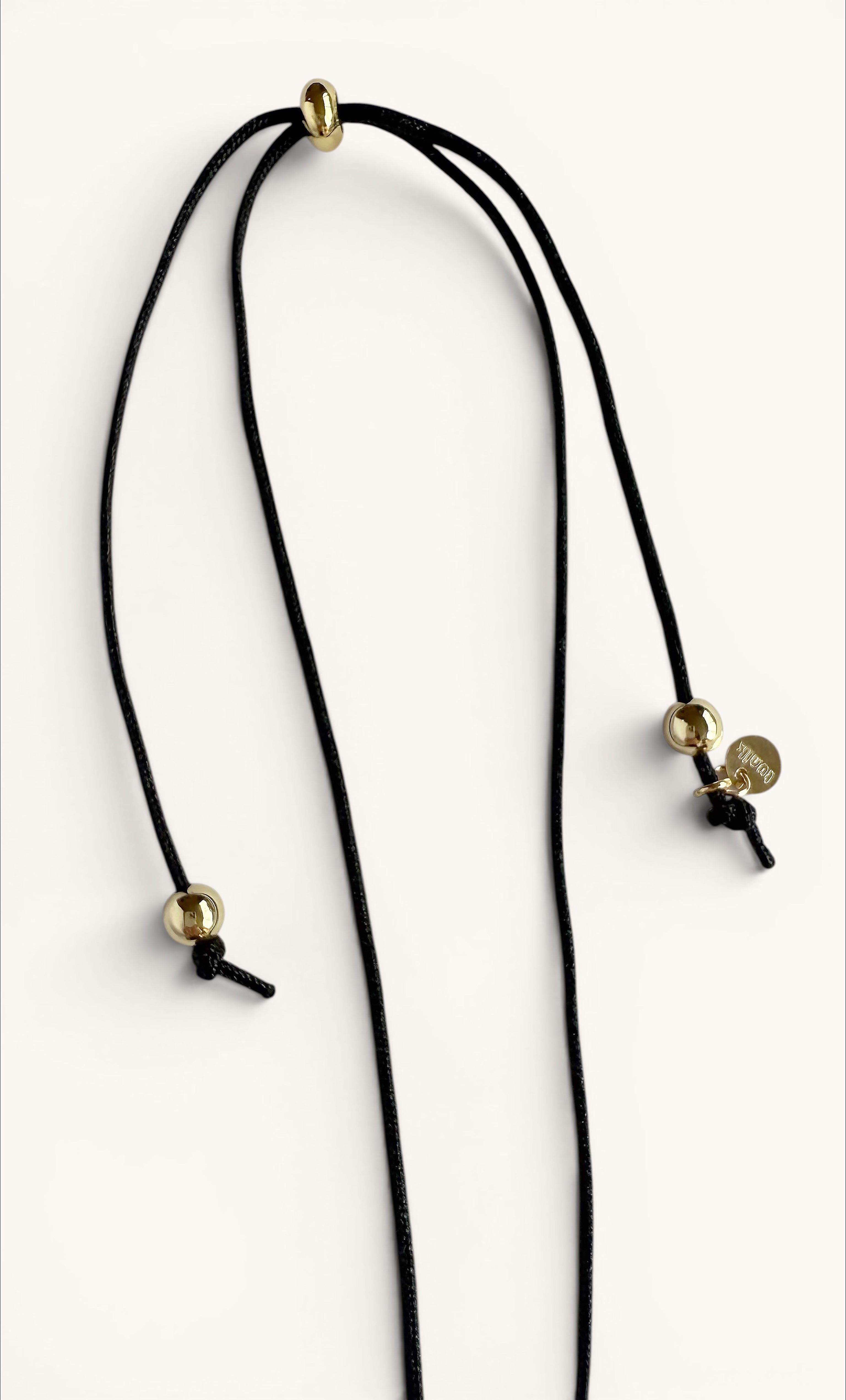 Long black cord necklace with small gold-filled beads and a single freshwater blister pearl pendant, minimalist design.