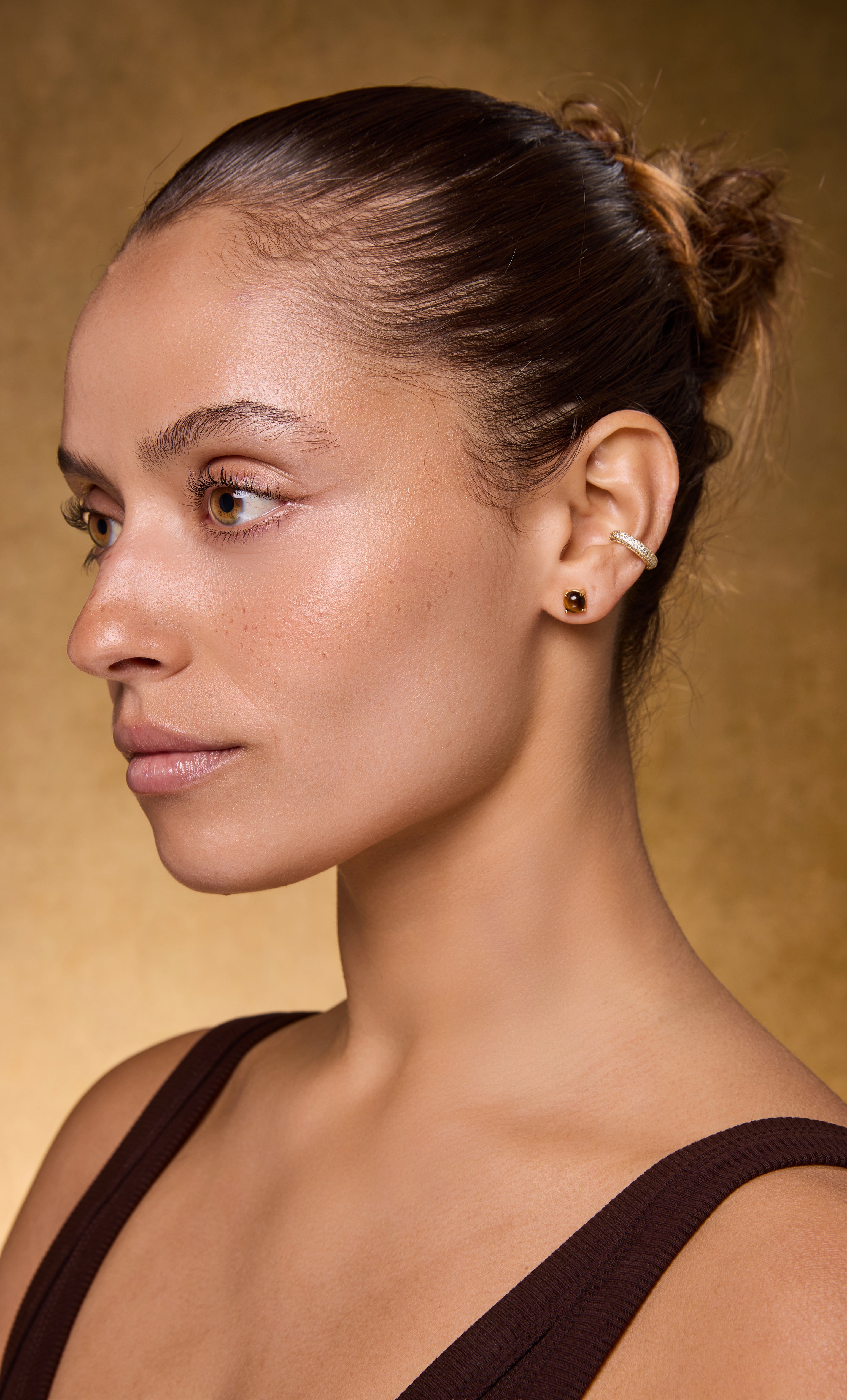14K gold fill tiger’s eye stud earrings by Tunik the Label on model with gold necklace and brown top.