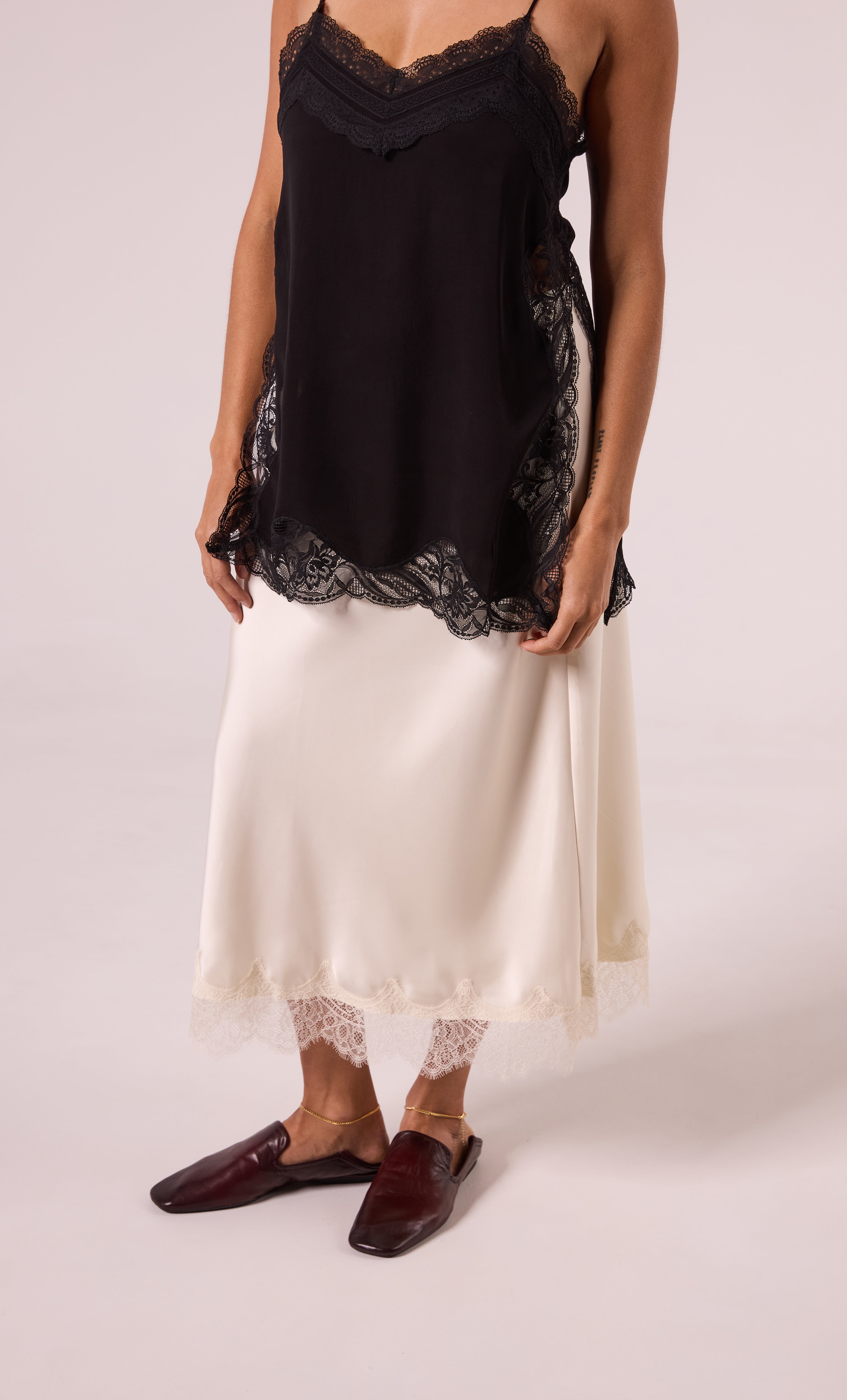 24K Gold Fill Fine Curb Chain Anklet by Tunik the Label on ankle, paired with black lace camisole and cream skirt, styled as .