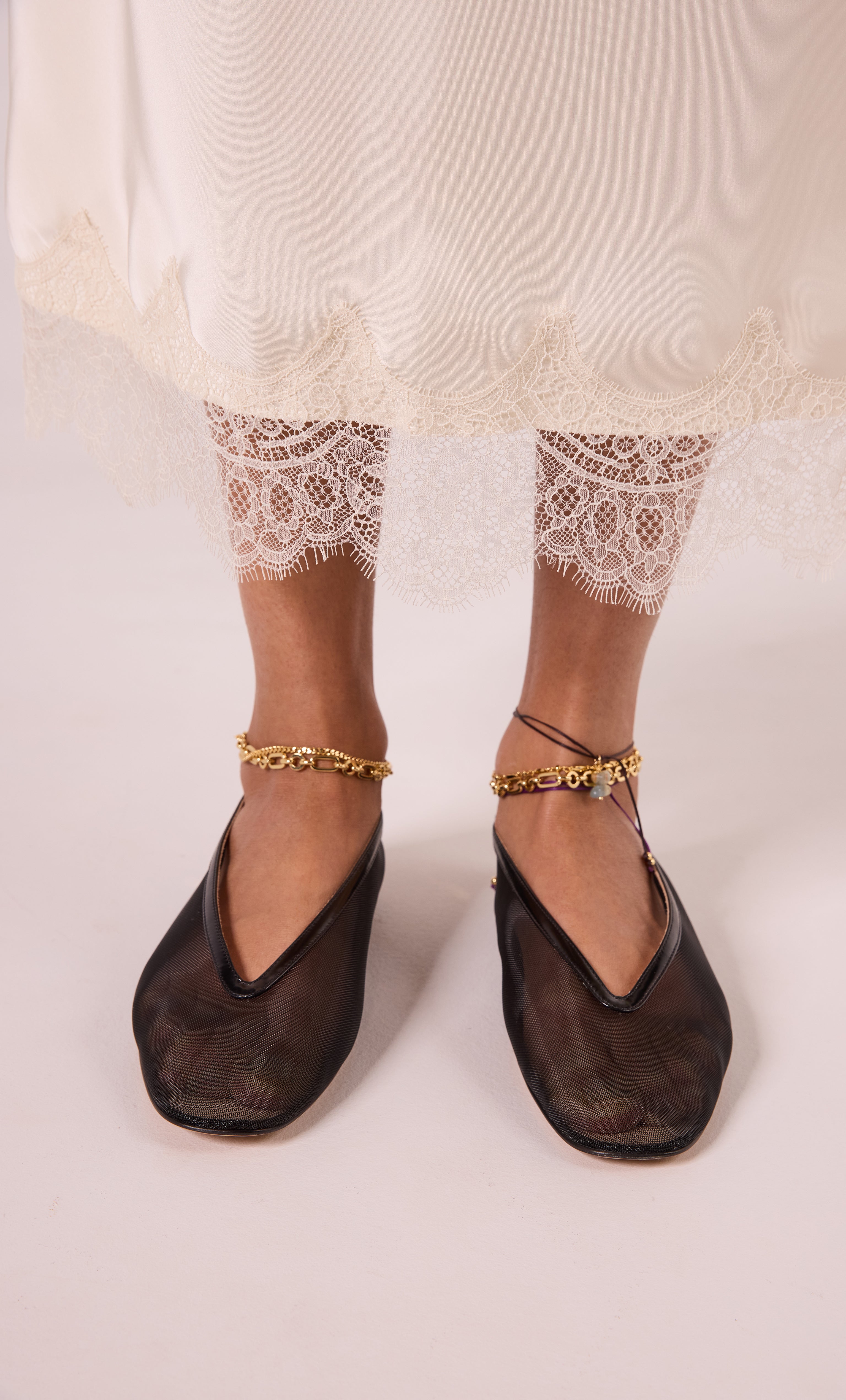 24K gold fill thick paper clip chain anklet by Tunik the Label on bare ankles paired with lace-trim white pants and black.
