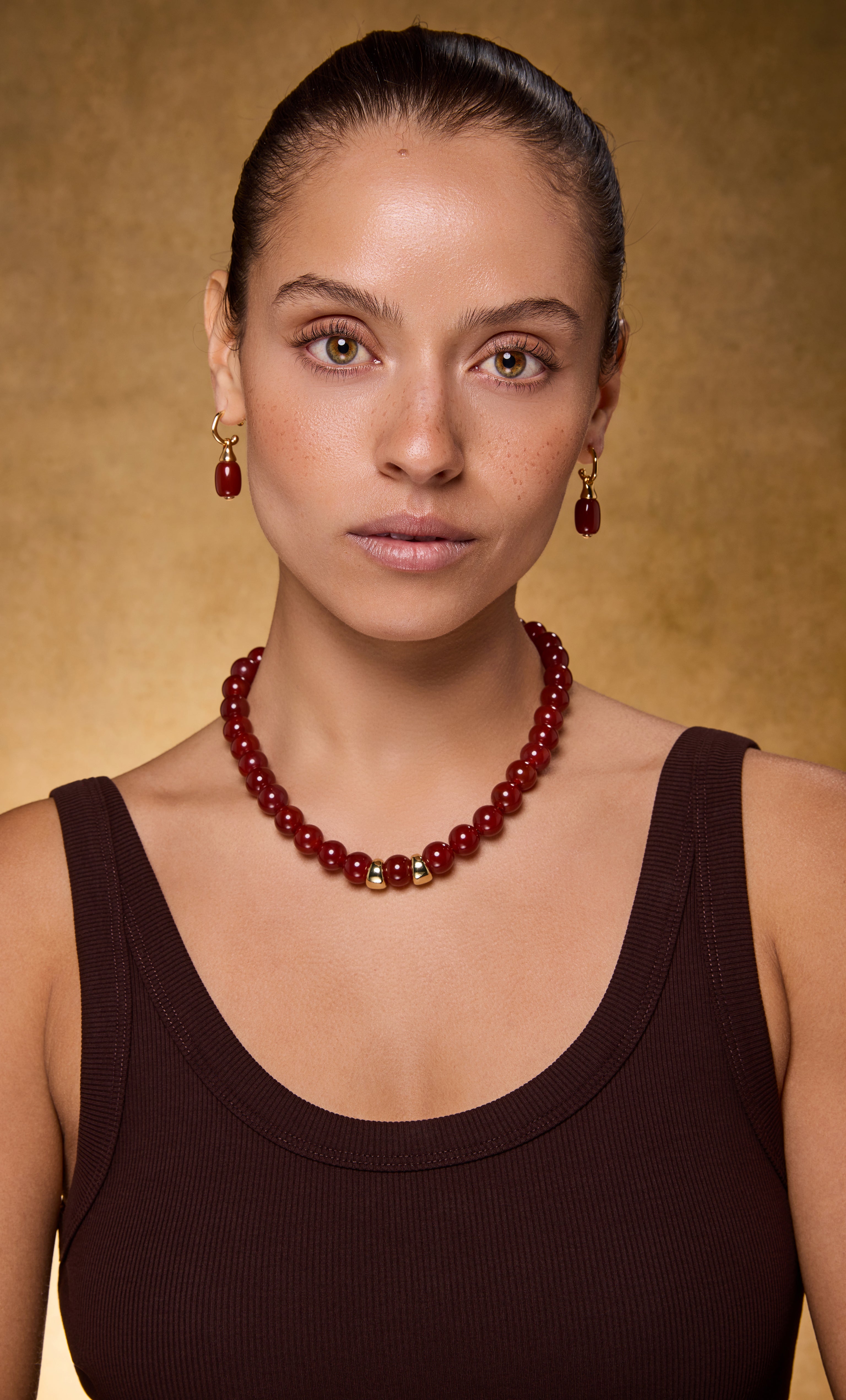 Tunik gold fill drop hoop earrings with carnelian red stone, paired with matching carnelian necklace and gold necklace.
