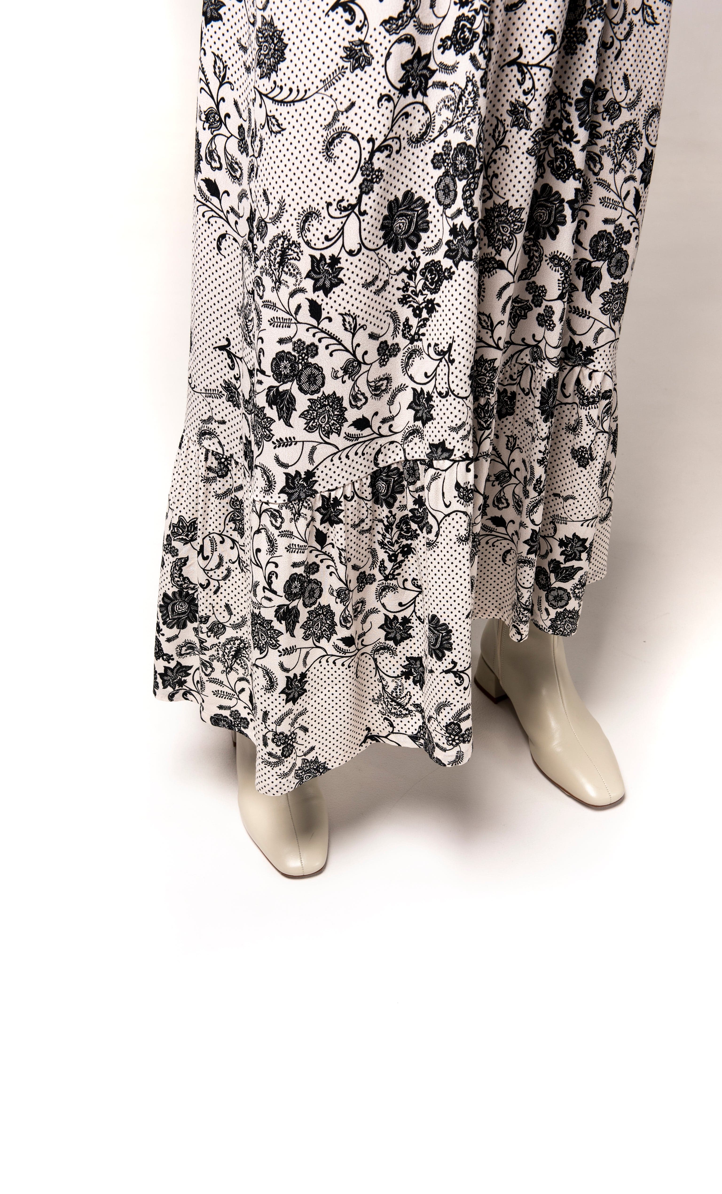 Flowy Lola Maxi Dress by Tunik with black paisley floral print on white fabric, paired with gold fill necklace from Tunik.