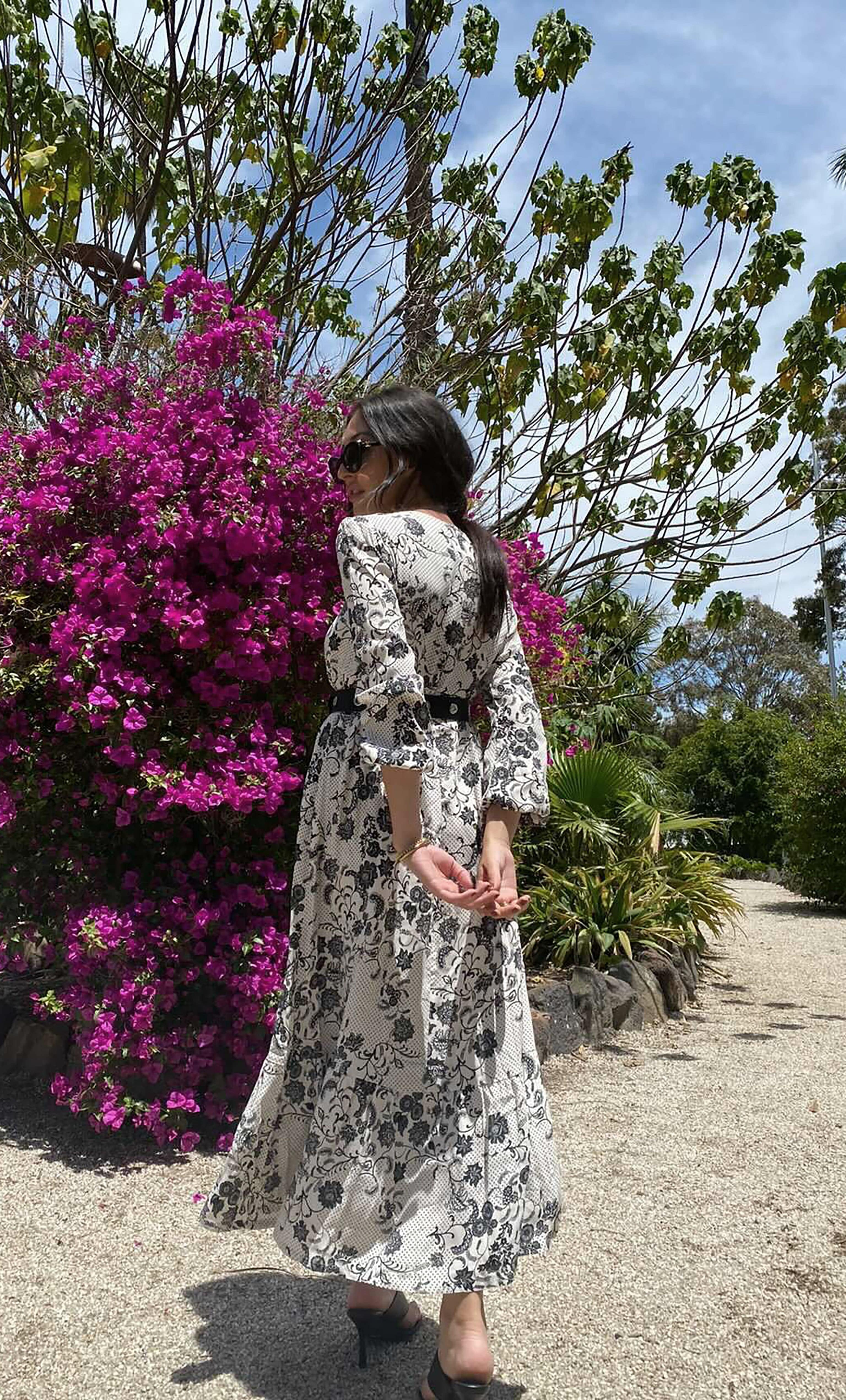 Tunik Lola Maxi Dress in black and white paisley floral print with long sleeves, styled with gold fill necklace from Tunik.