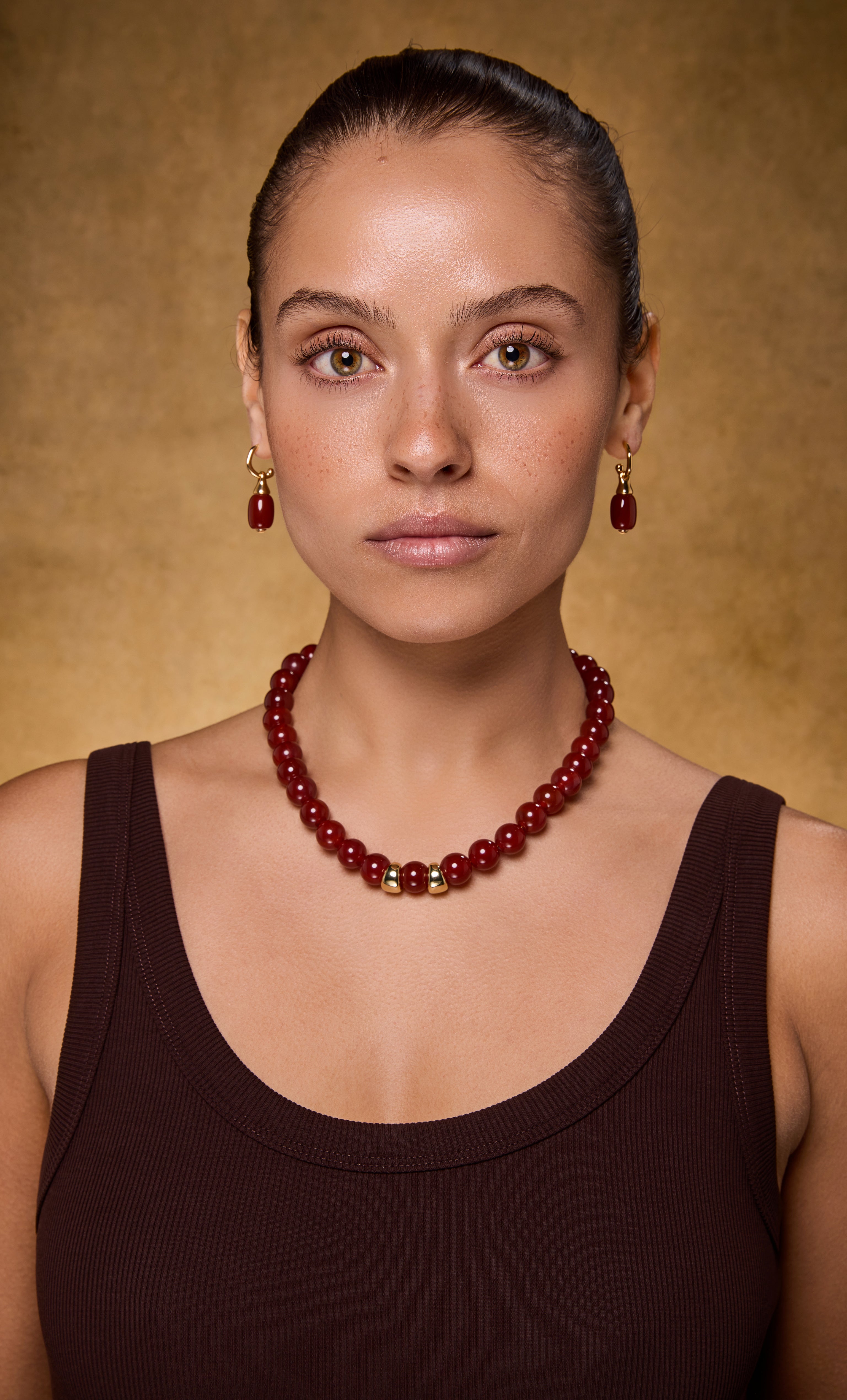 Tunik gold fill drop hoop earrings with carnelian red stones paired with matching carnelian bead necklace and gold accents.