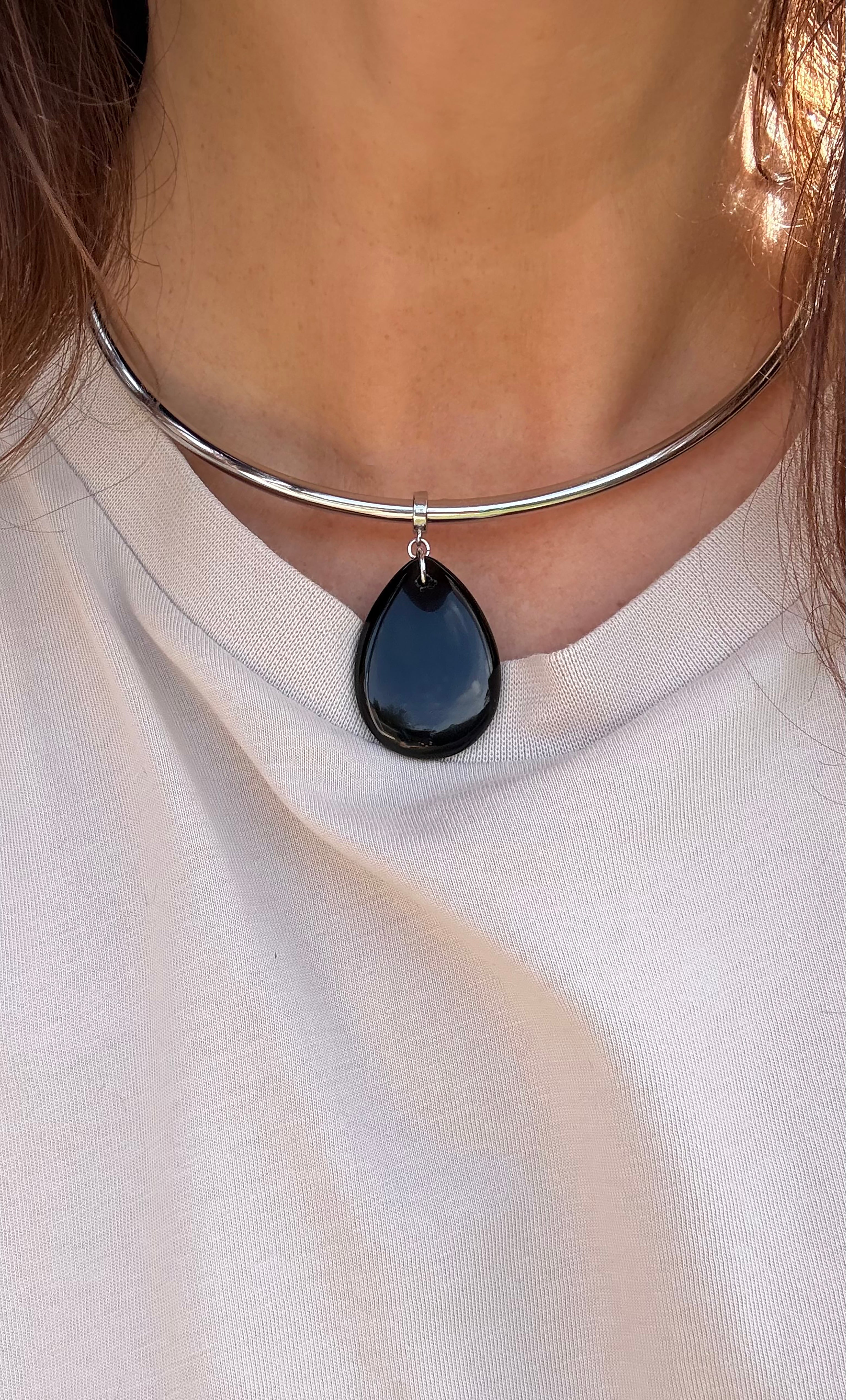 Silver collar necklace with a teardrop-shaped black agate stone pendant on a short, smooth band.