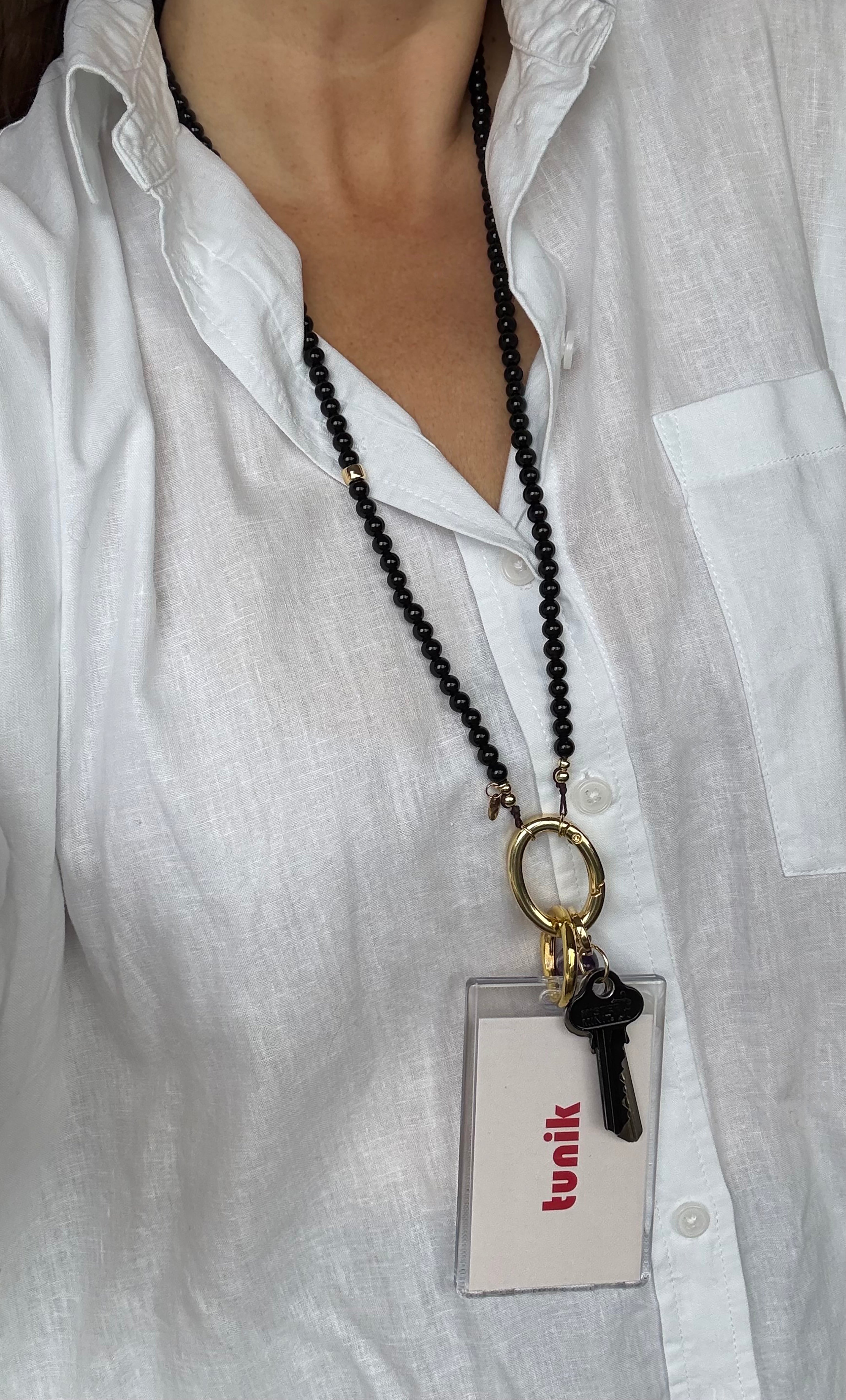 Long black agate bead necklace with 14K gold fill clasp holding keys and clear cardholder pendant.