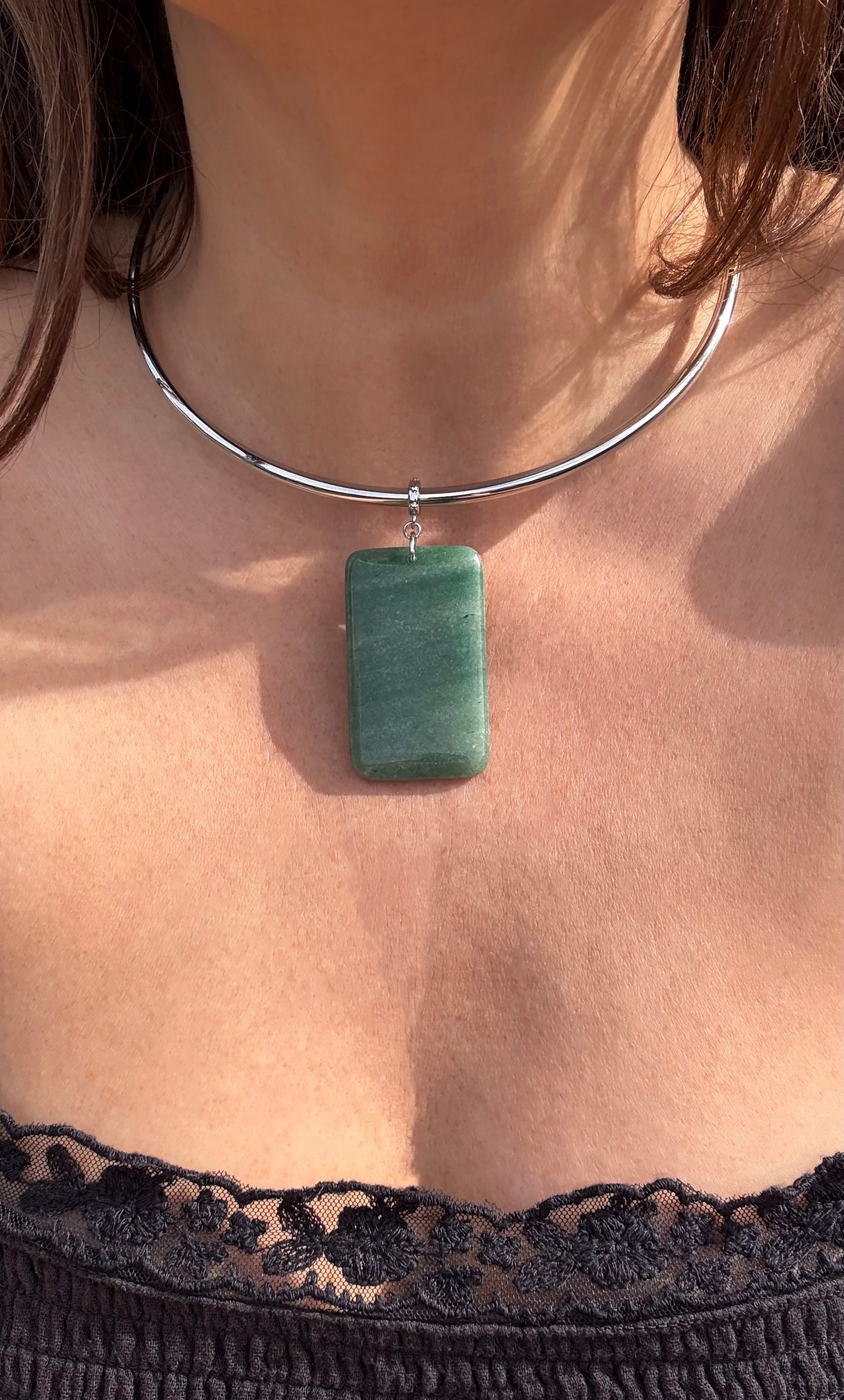 Silver collar necklace with rectangular green aventurine pendant resting above lace-trimmed black top.