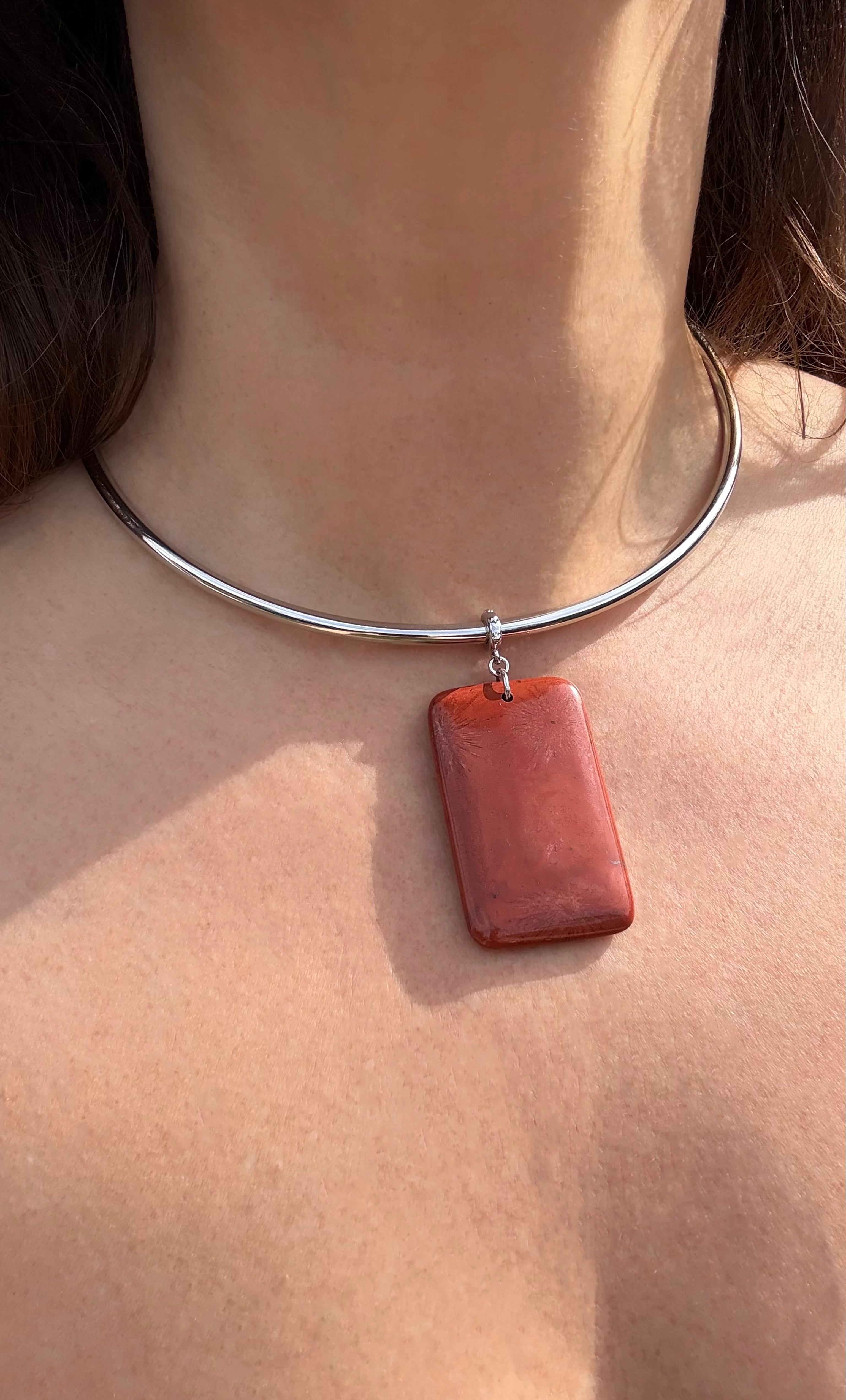 Silver collar necklace with rectangular deep red jasper pendant resting on collarbone.