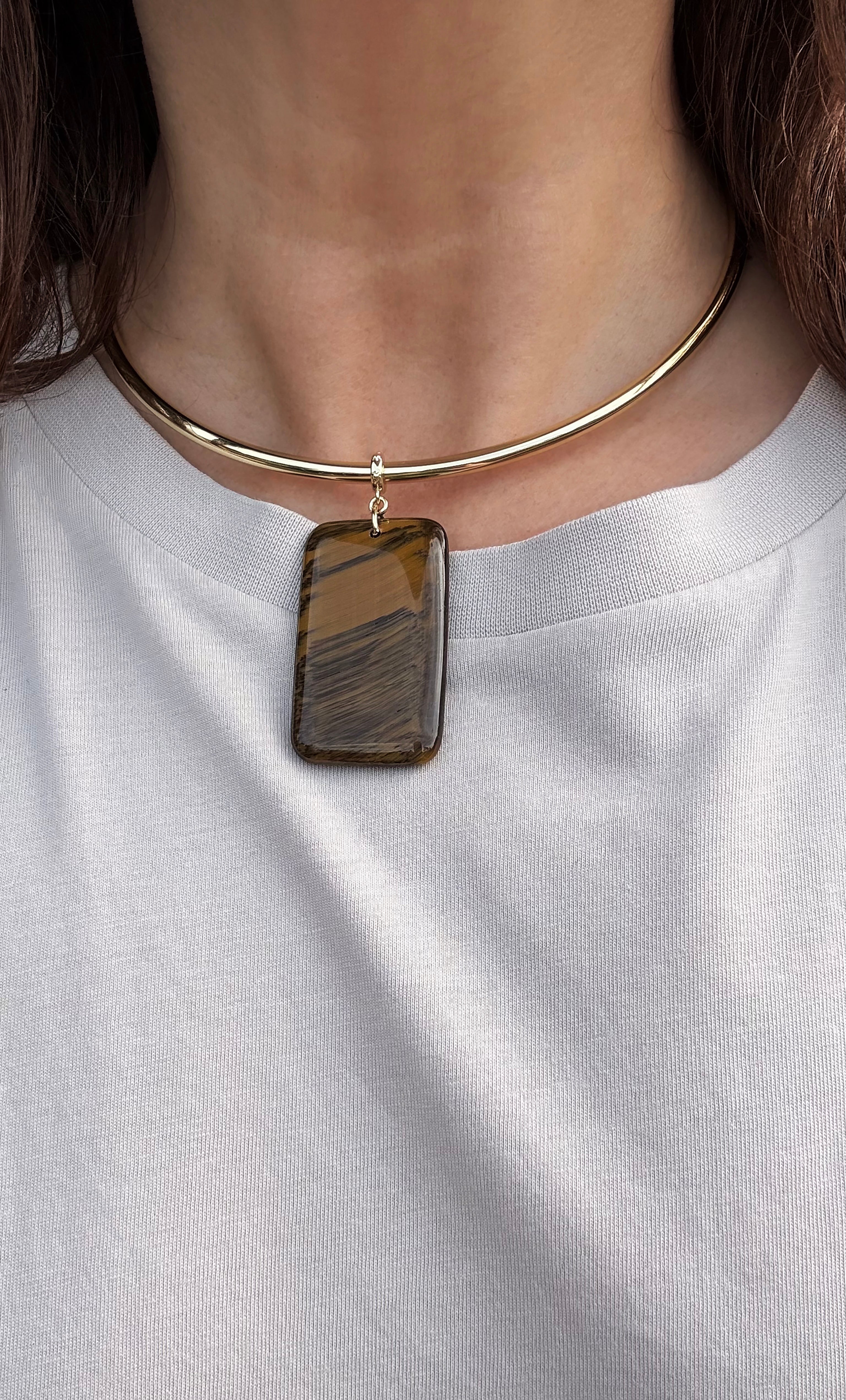 Gold fill collar necklace with rectangular tigers eye pendant on model wearing white top.