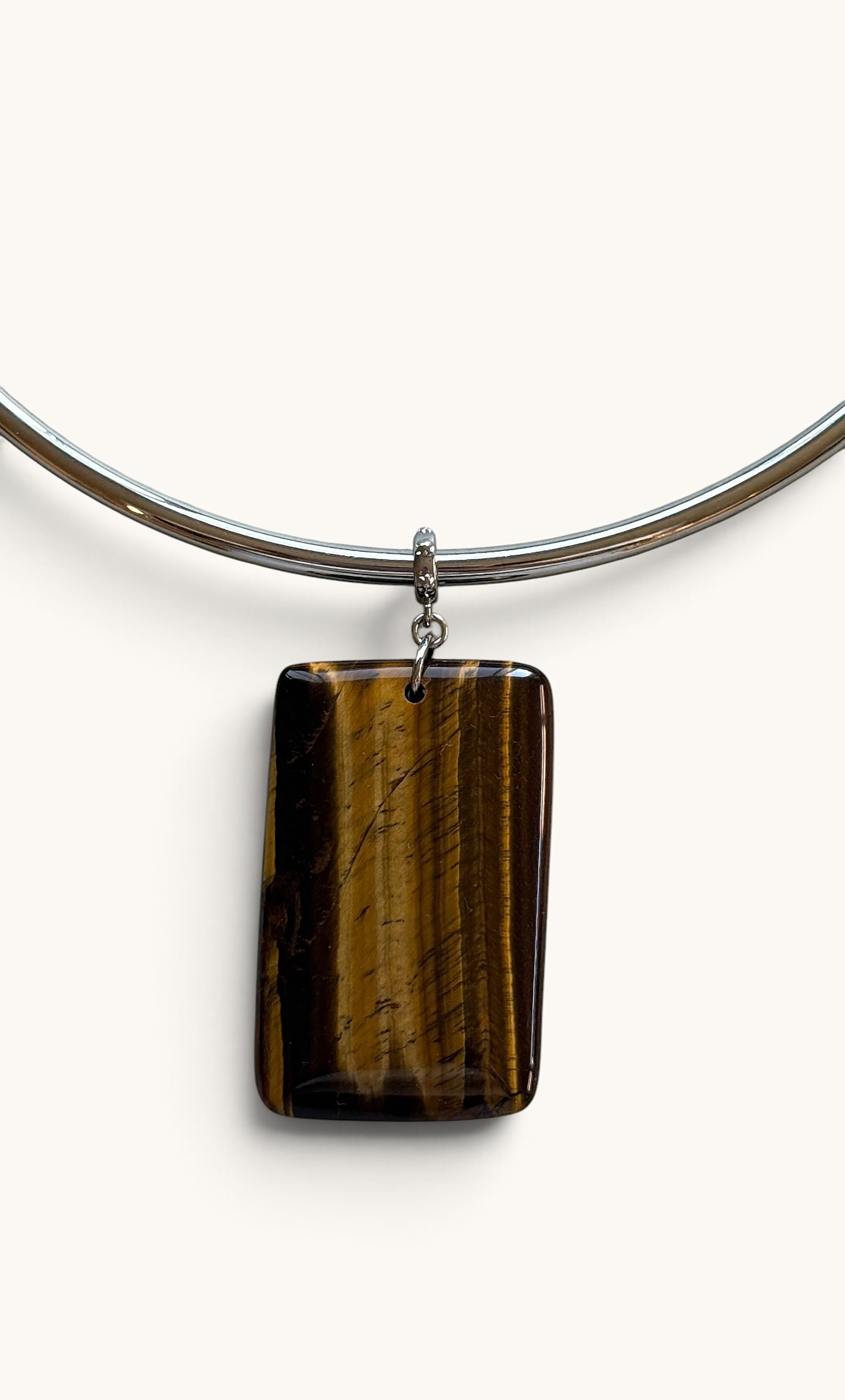 Rectangular tiger’s eye stone pendant with golden-brown striations on a sleek silver collar necklace.