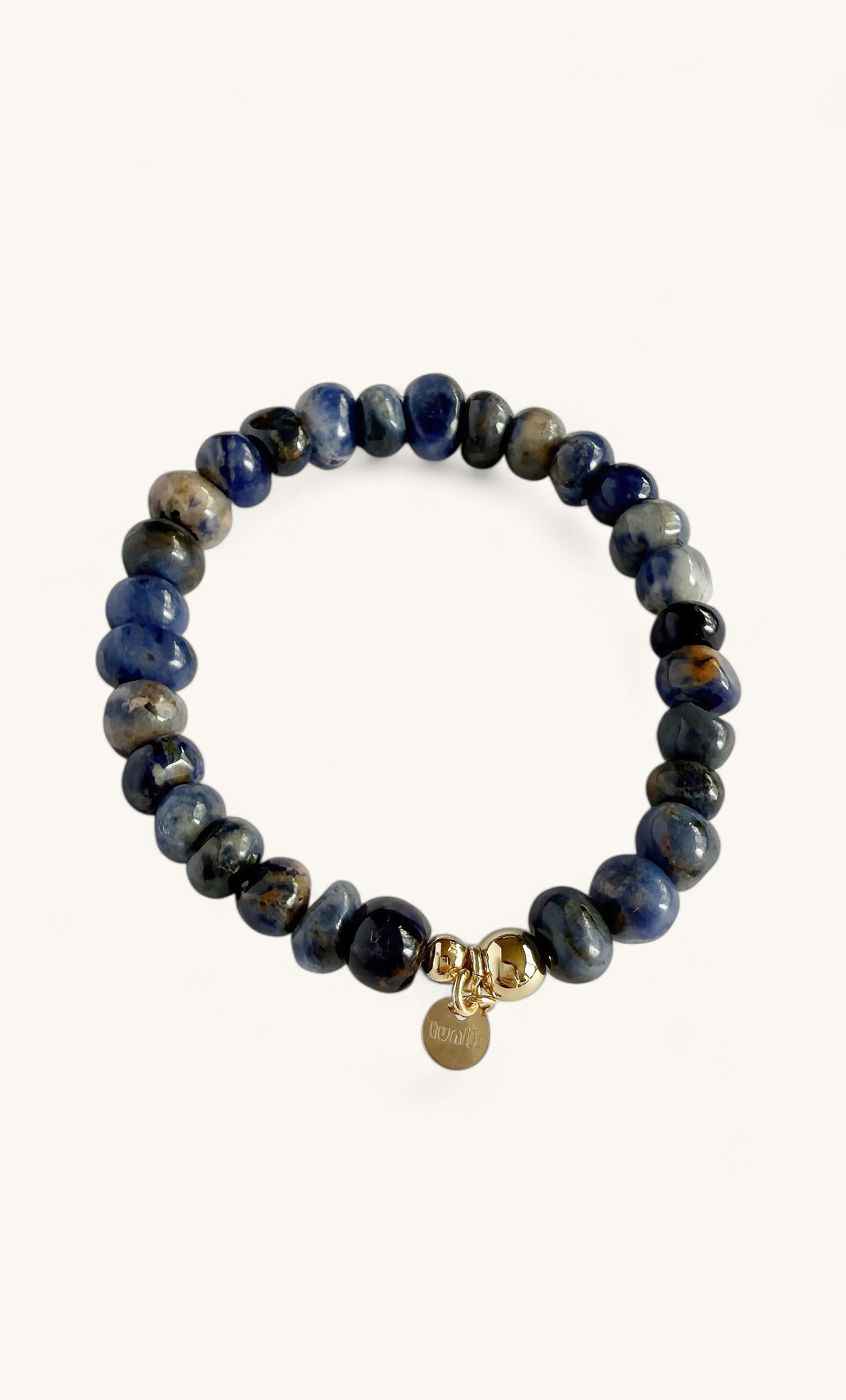 Circular bracelet with polished blue sodalite beads and a small gold clasp pendant.