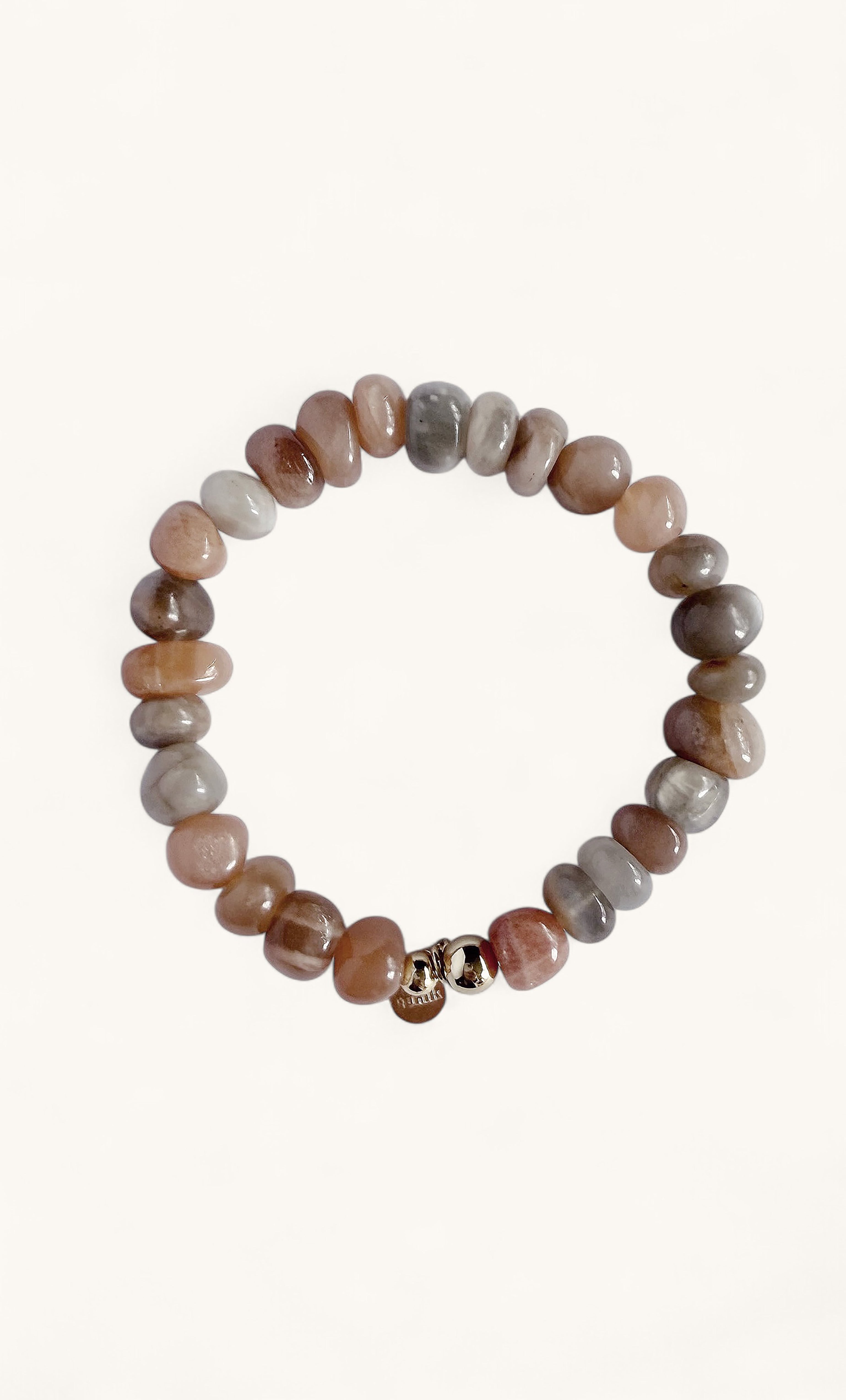 Round peach and gray moonstone beads strung in a stretch bracelet with a small gold charm.