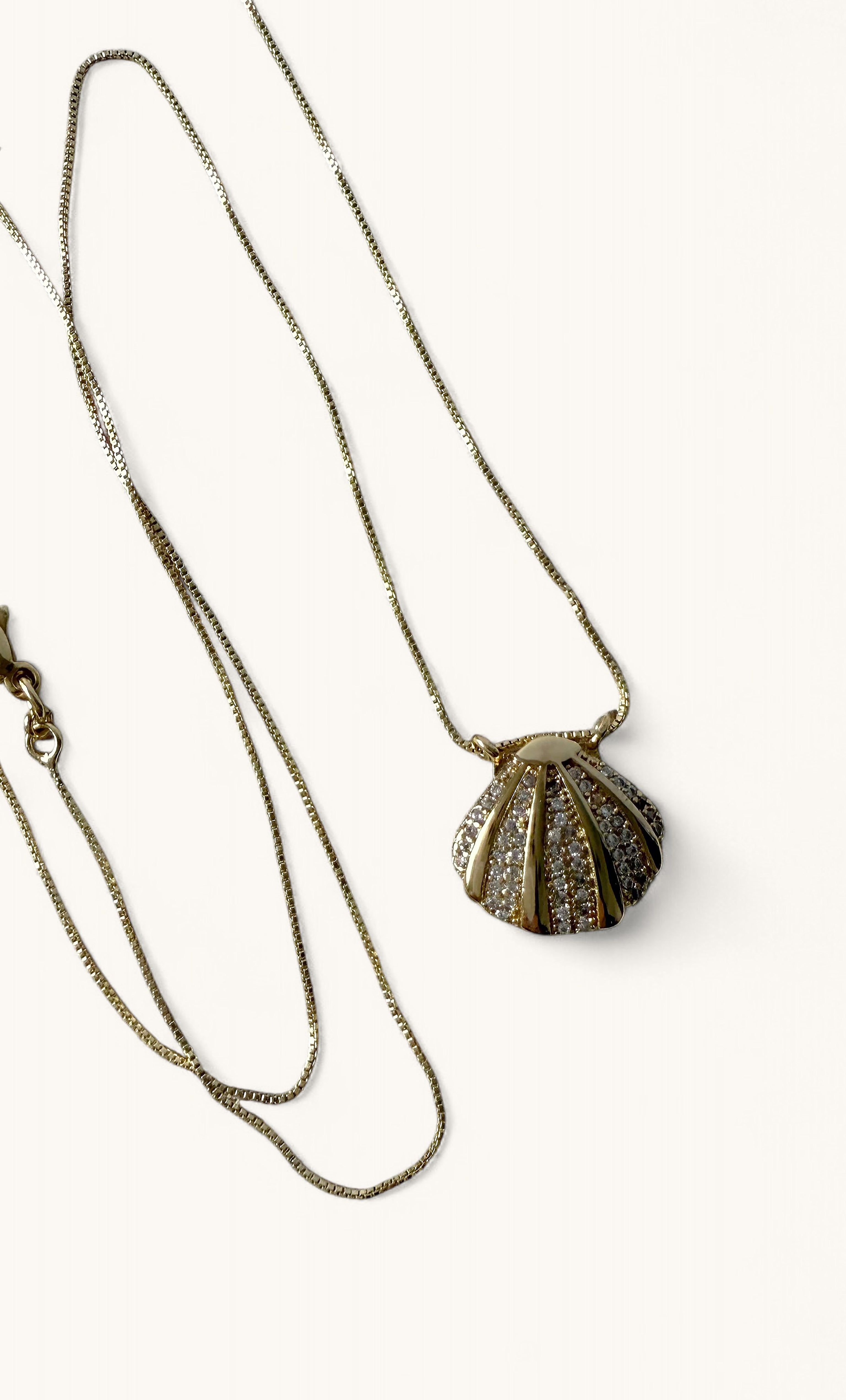 Delicate gold fill necklace with finely detailed clam shell pendant and thin chain by Tunik.