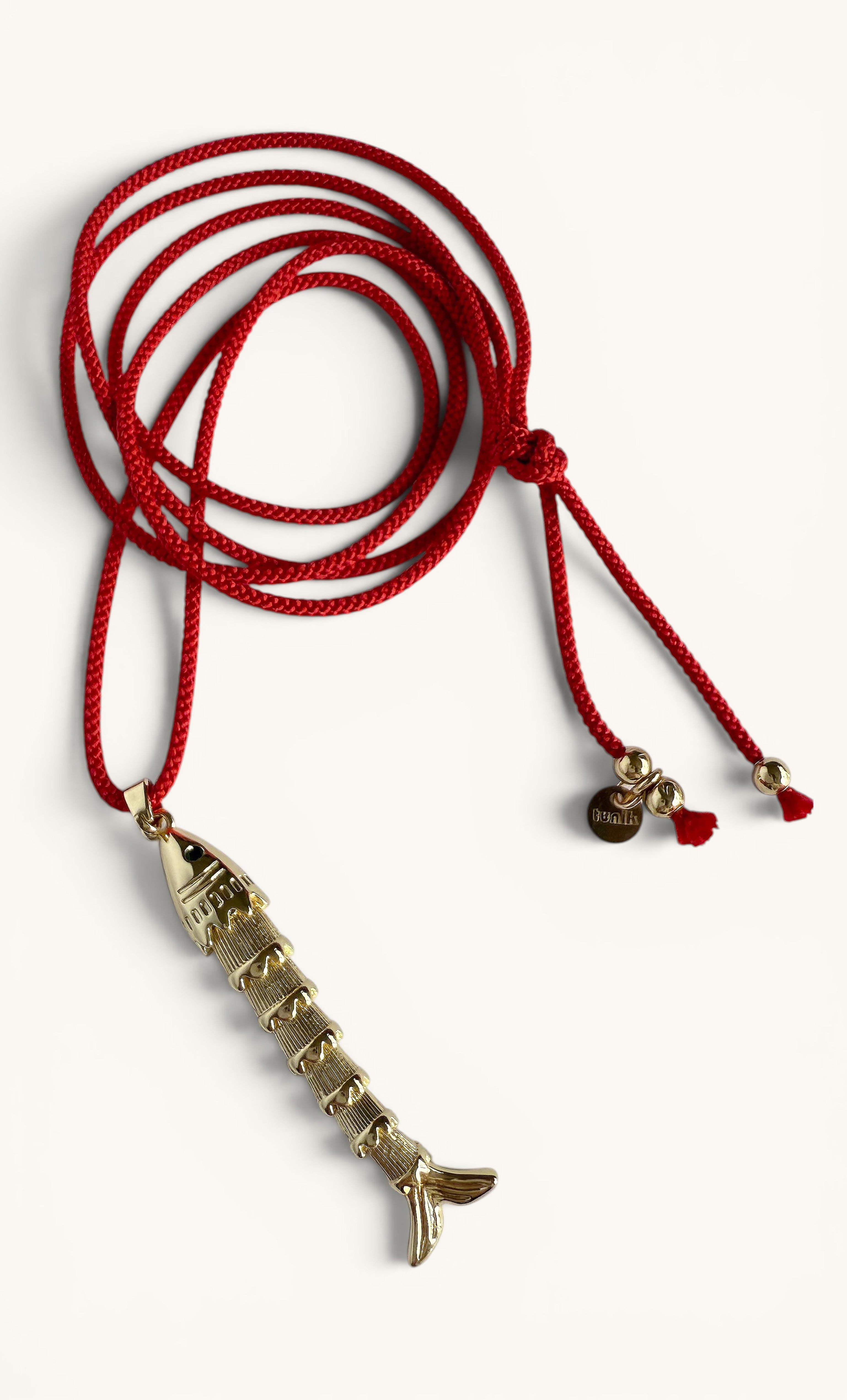 Gold koi fish pendant with detailed scales on a red Japanese cord necklace.