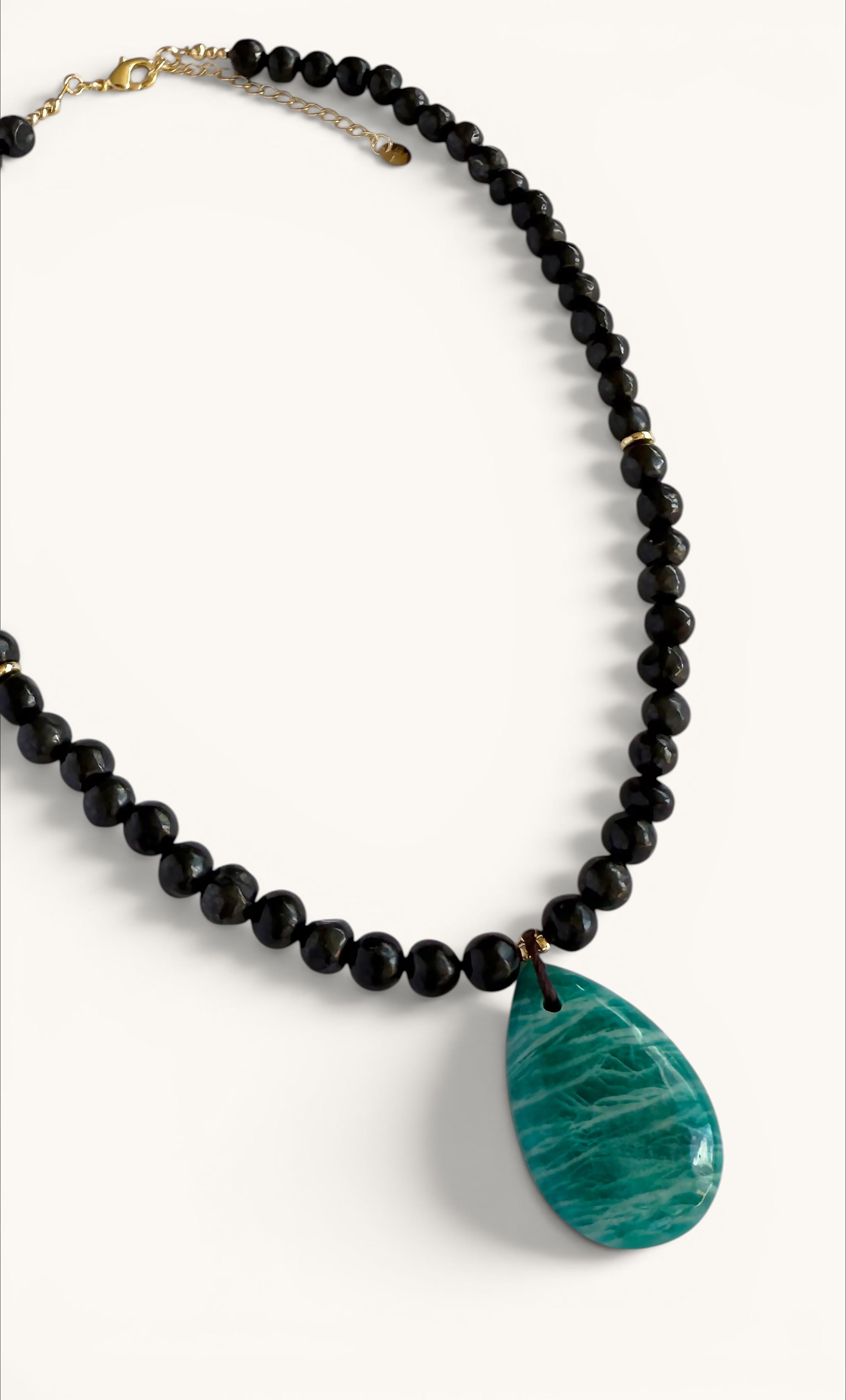 Gold-filled bead necklace with glossy black shungite pebbles and a teardrop-shaped natural amazonite pendant.