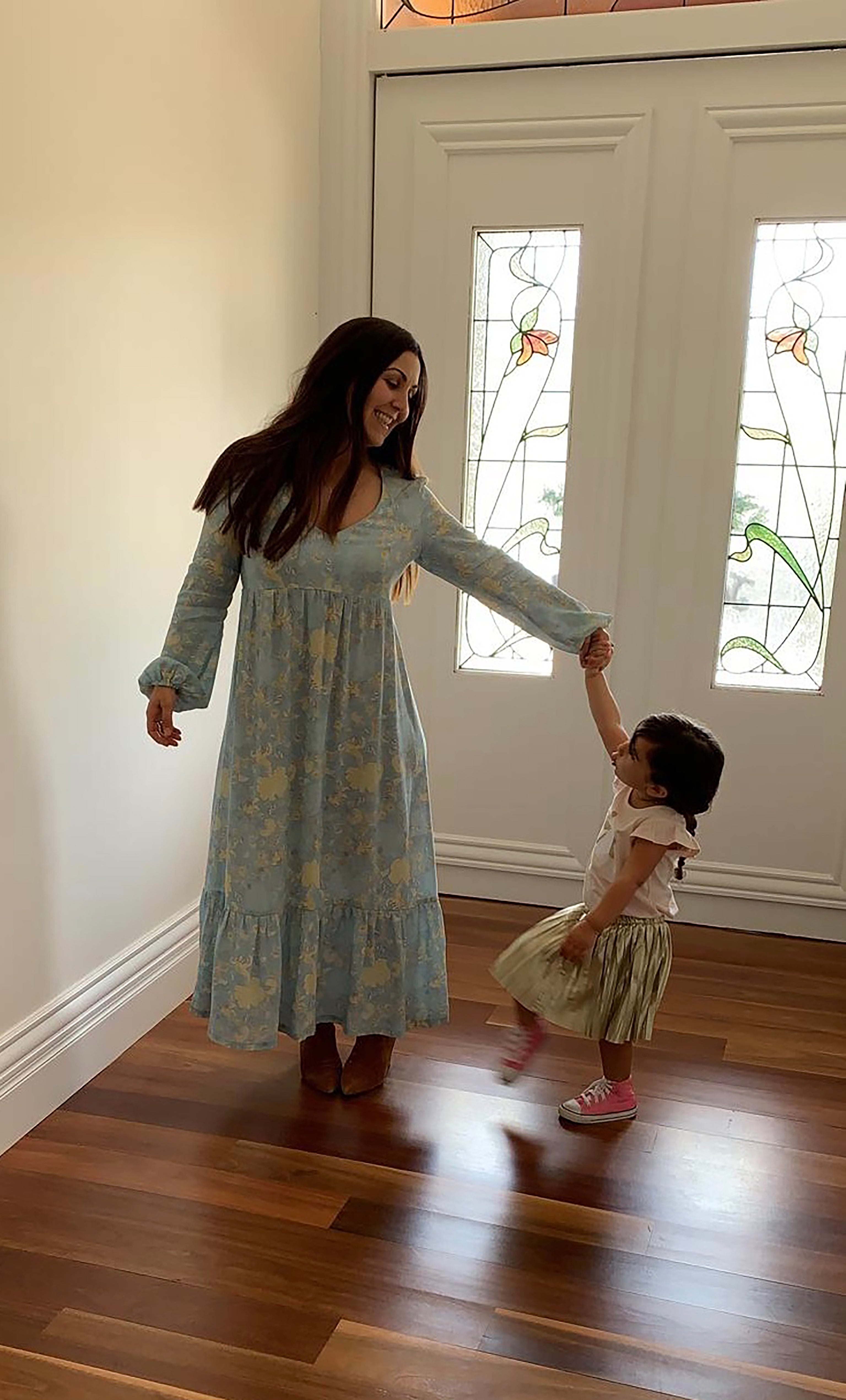 Tunik Lola maxi dress in Mystic Floral Aquamarine print with gold fill necklace from Tunik The Label, styled with child in.