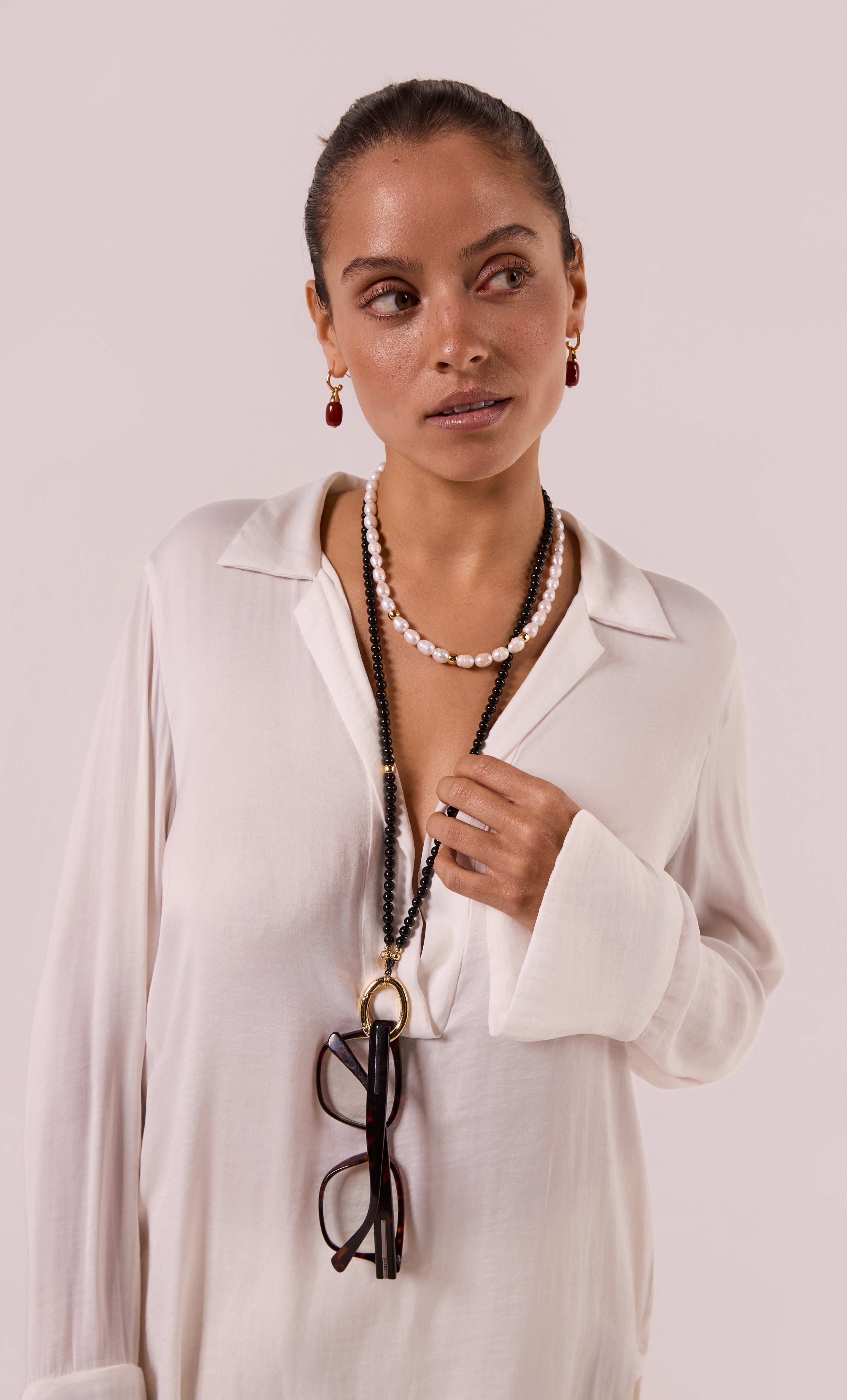 Tunik gold fill necklace with semi-precious pearls layered over white blouse, paired with matching earrings and eyeglasses.